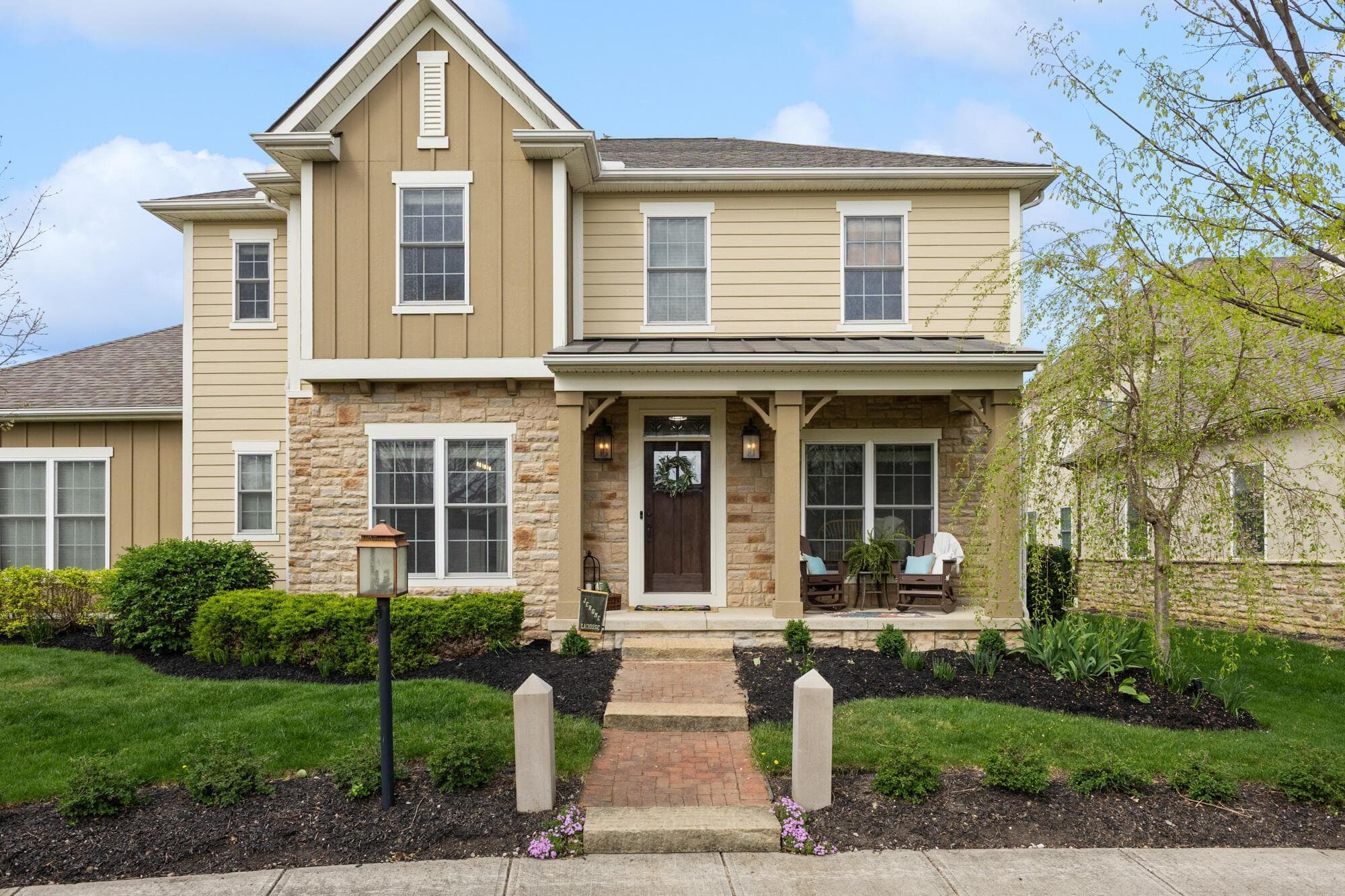 Front facade showcasing stone and fiber cement siding, covered entry porch, and symmetrical window placement under a pitched roof.