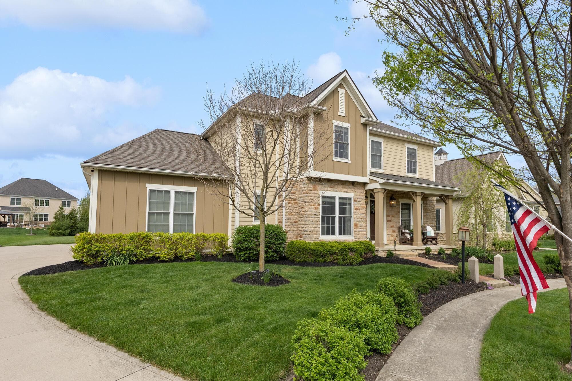 Angled street view of the home showing the curved driveway, established trees, and manicured front beds on a generous lot.