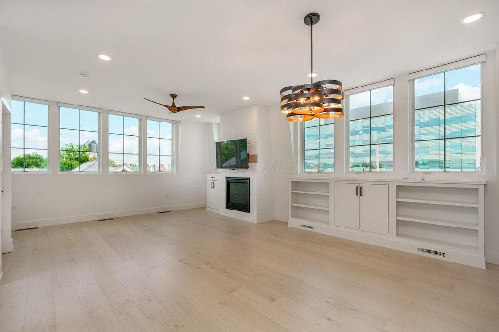 This expansive great room is flooded with natural light and features custom built-ins, motorized custom blinds and gas log fireplace.