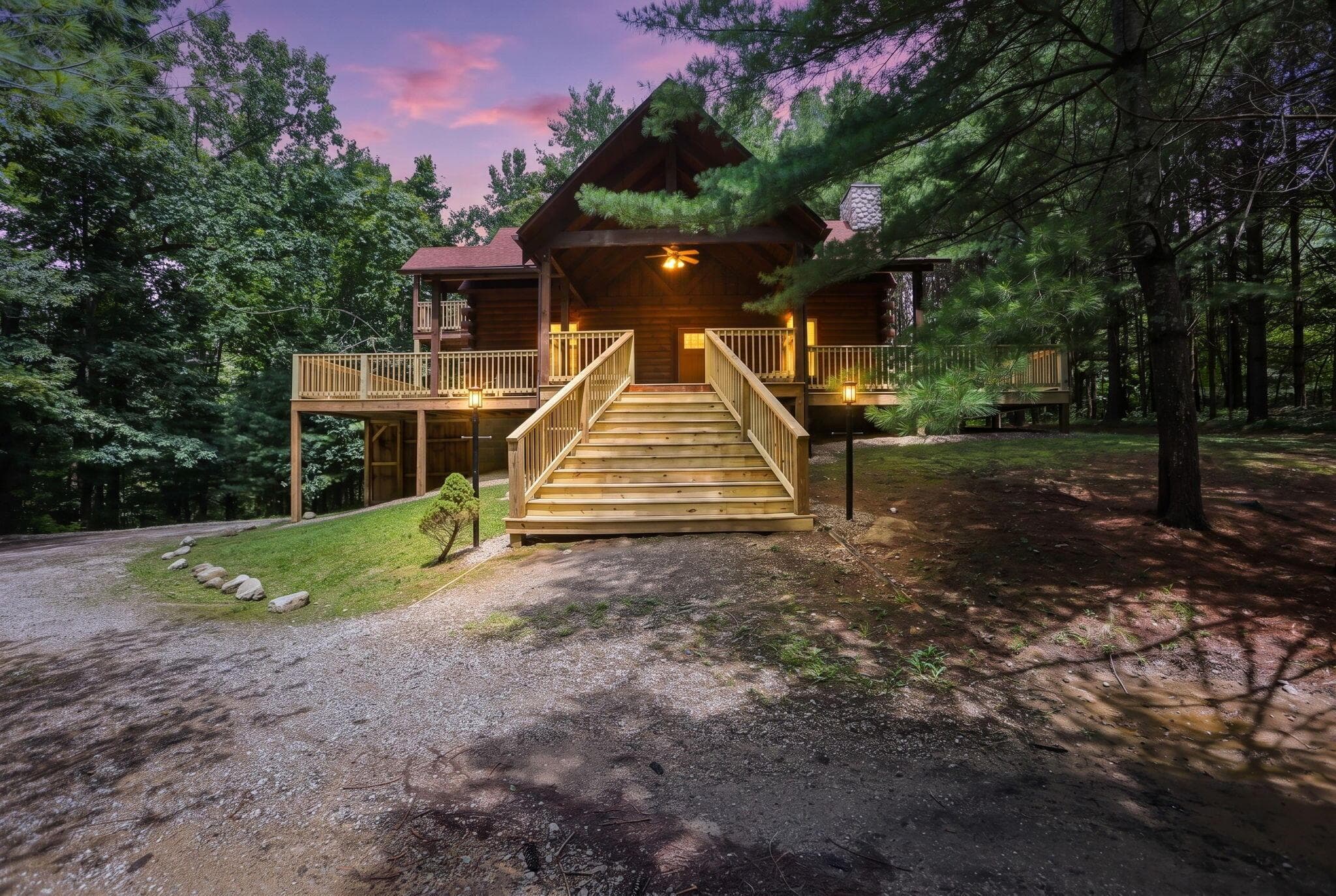 Log home featuring a prominent front staircase, an elevated porch with wood railings, and a stone chimney