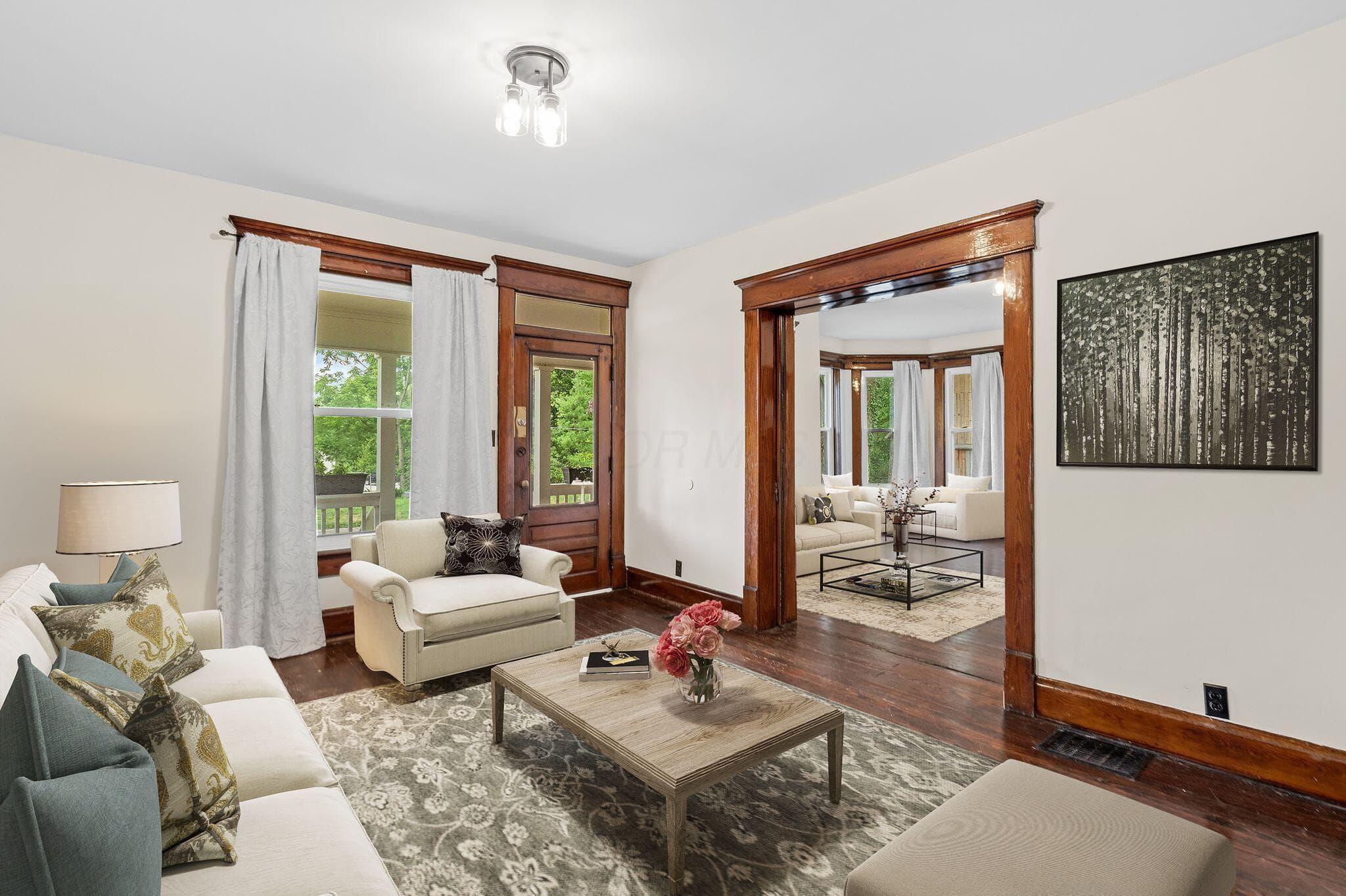 Virtual Staging. Spacious room featuring rich wood-finish flooring, wide trim, and a decorative doorway