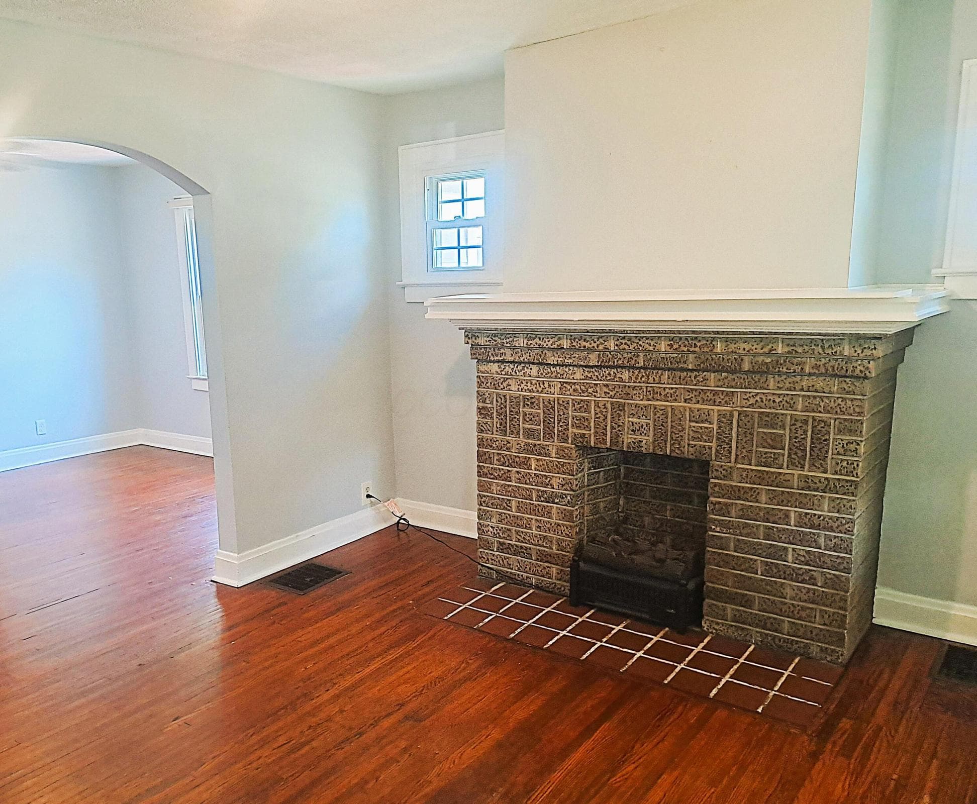 View of your front living room and decorative fireplace. A large mantle will let you customize the space of this charming focal point to your liking. The electric insert remains for the buyer.