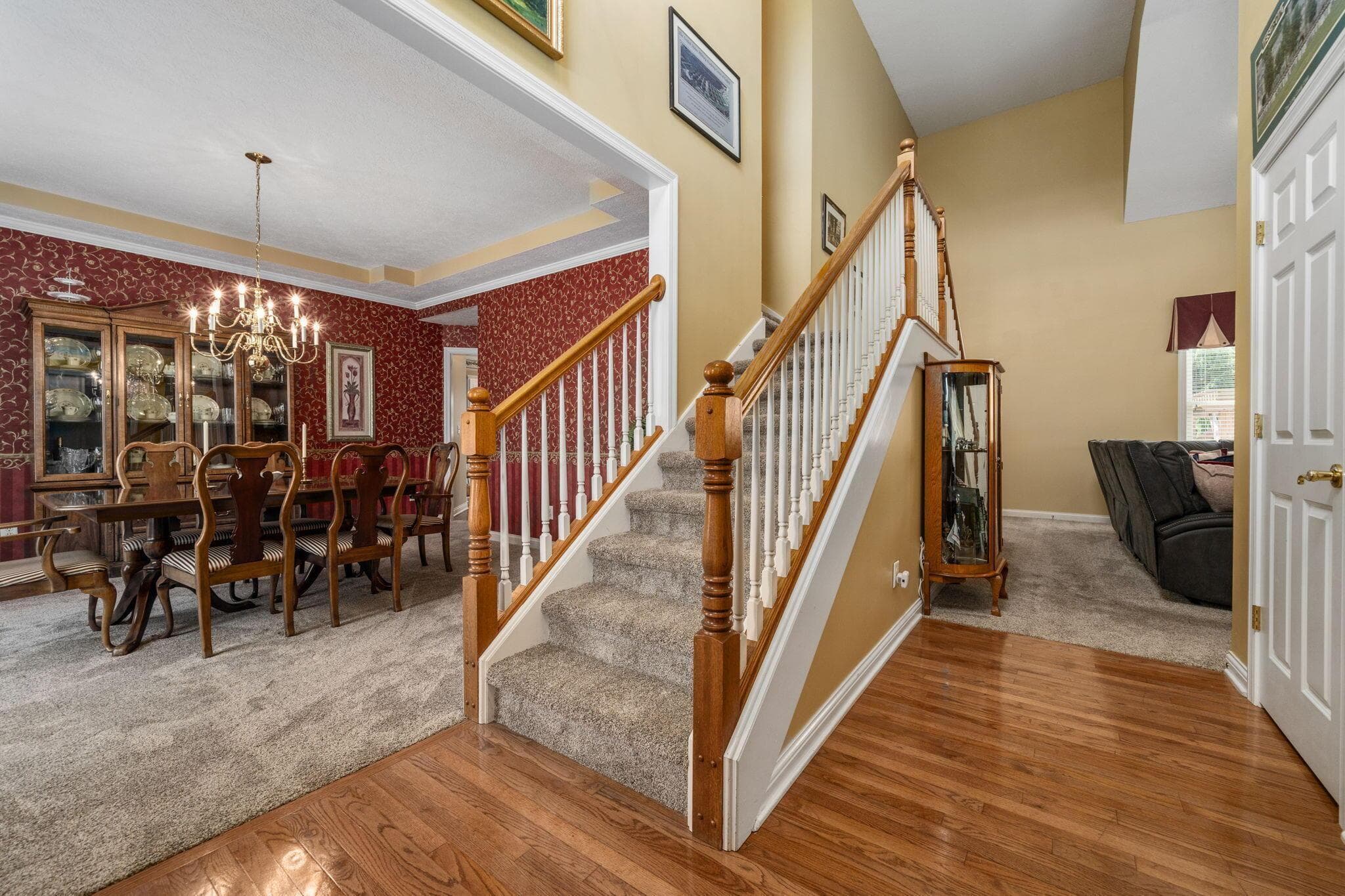2 story entry with neutral walls, hardwood floors and painted white trim.