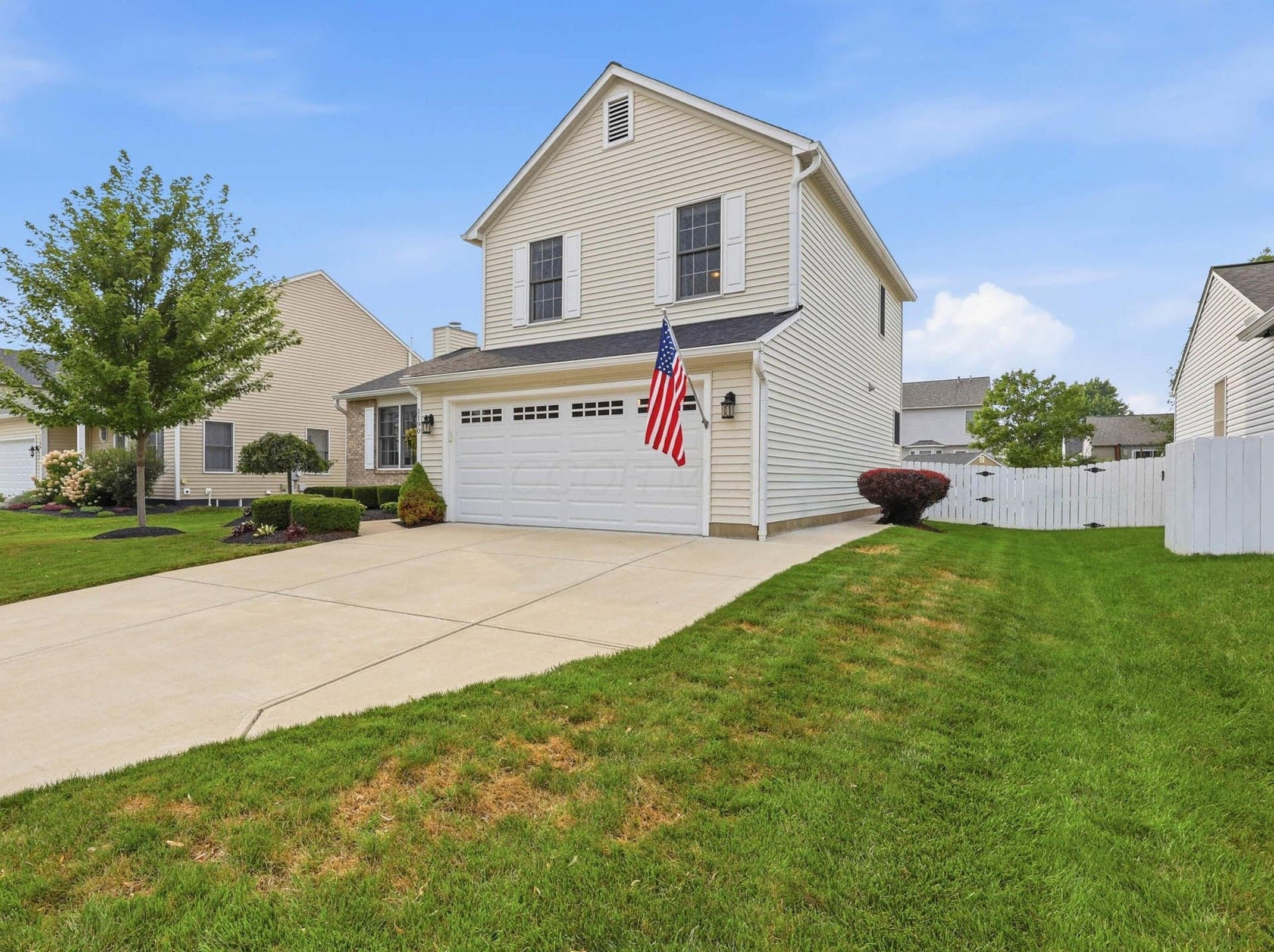 Two-story residence featuring light-toned siding and a prominent two-car garage