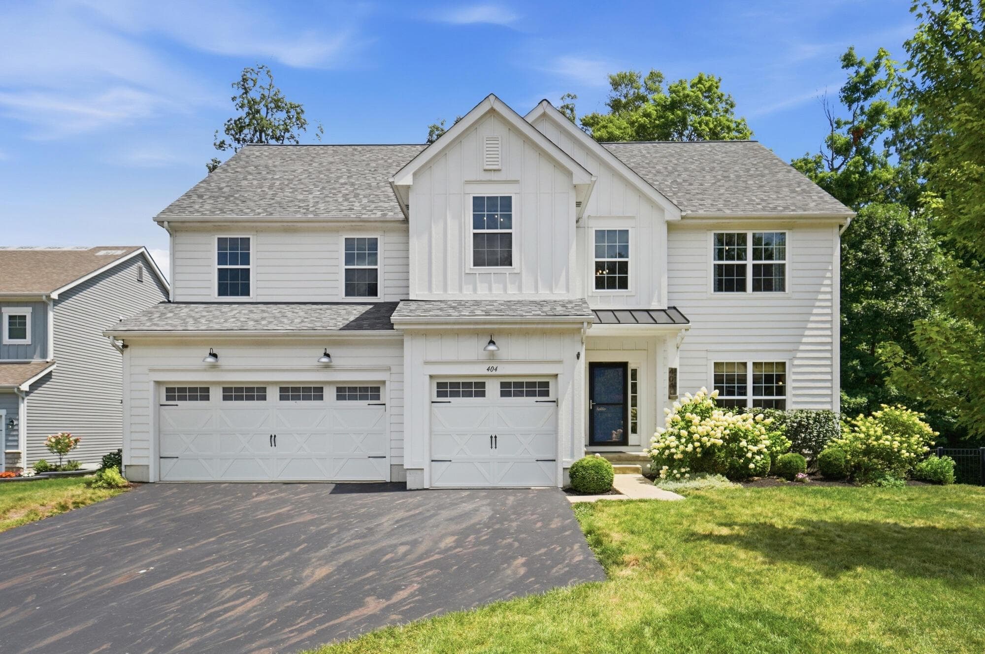 Modern farmhouse-style exterior featuring white horizontal siding, board and batten accents, and a three-car garage