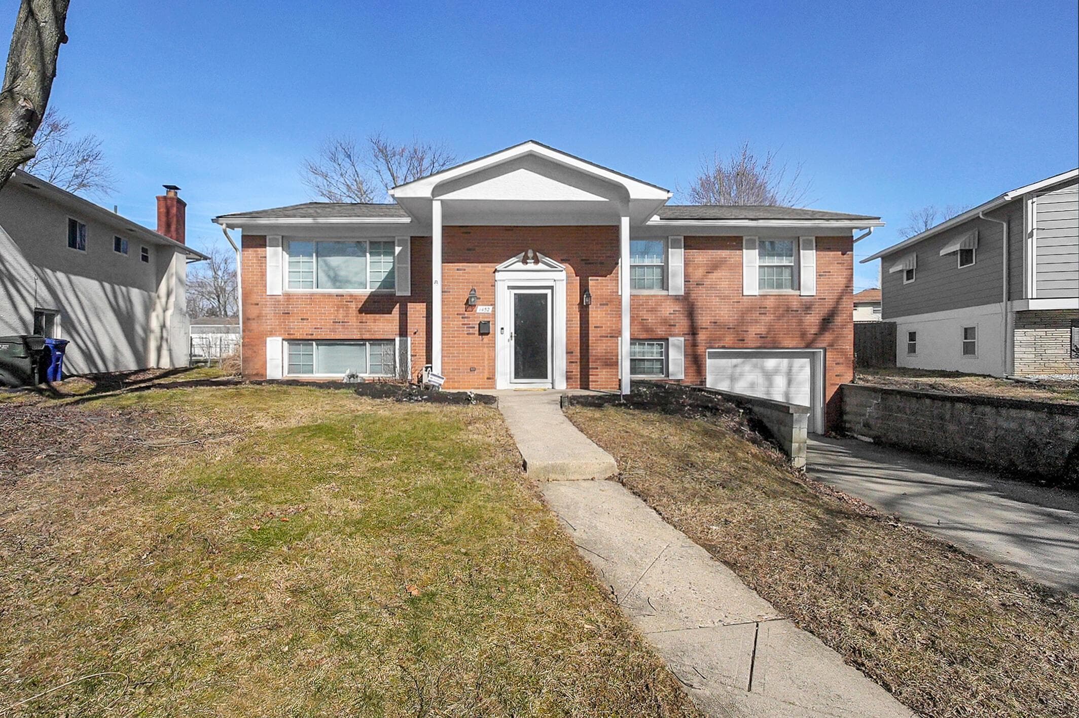 Brick exterior residence featuring a covered front entry, an attached garage, a paved driveway, and a front walkway