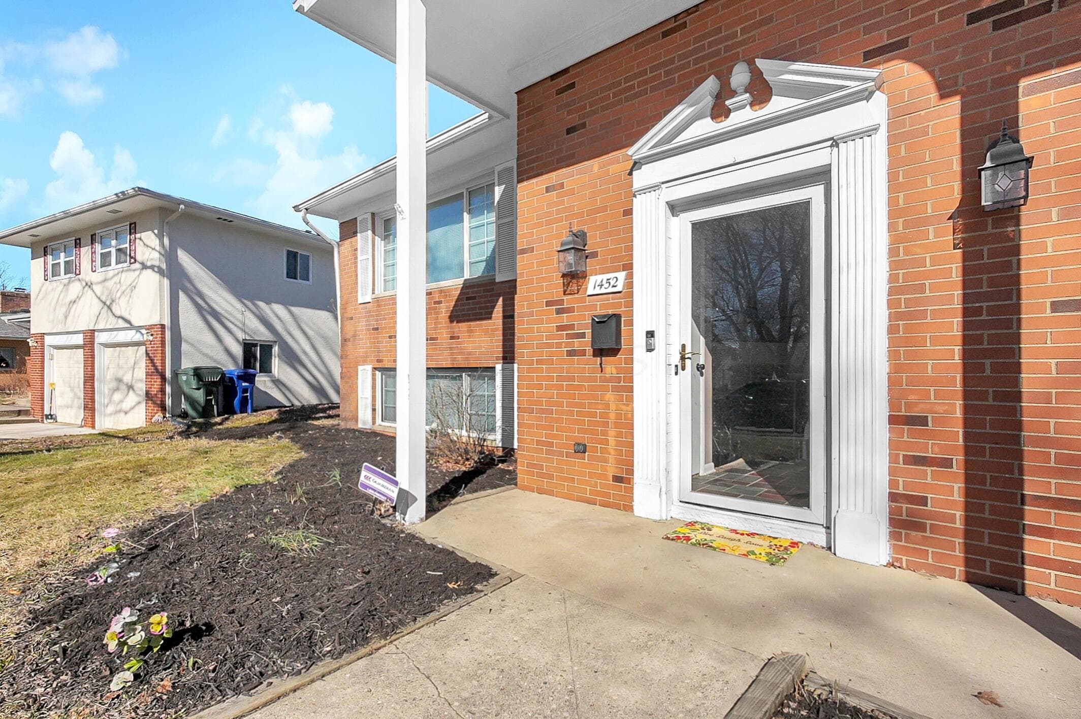 Brick exterior featuring a decorative white entryway surround, a storm door, and exterior sconce lighting