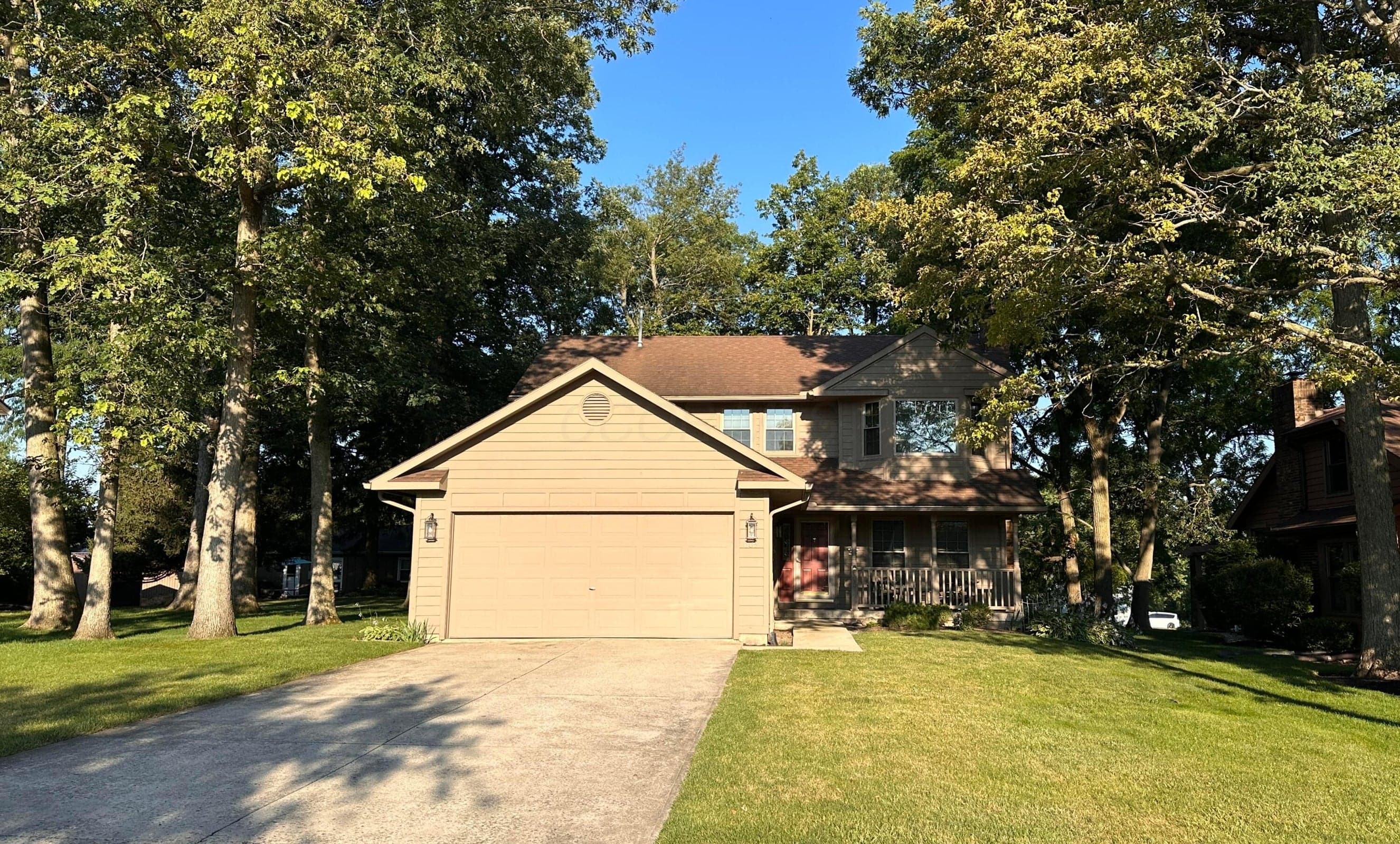 Two-story residence featuring light brown siding and a brown shingled roof