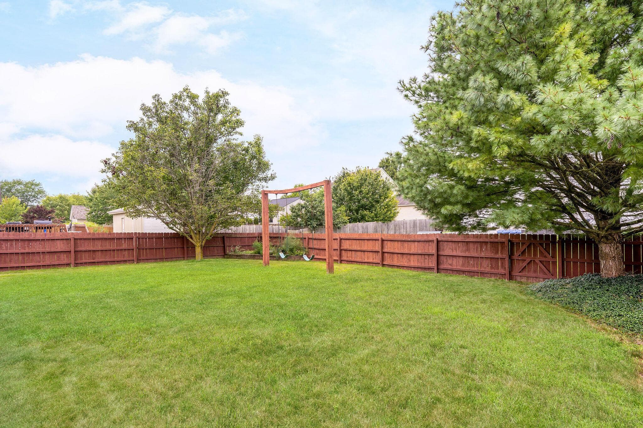 Expansive green lawn surrounded by a stained wood privacy fence