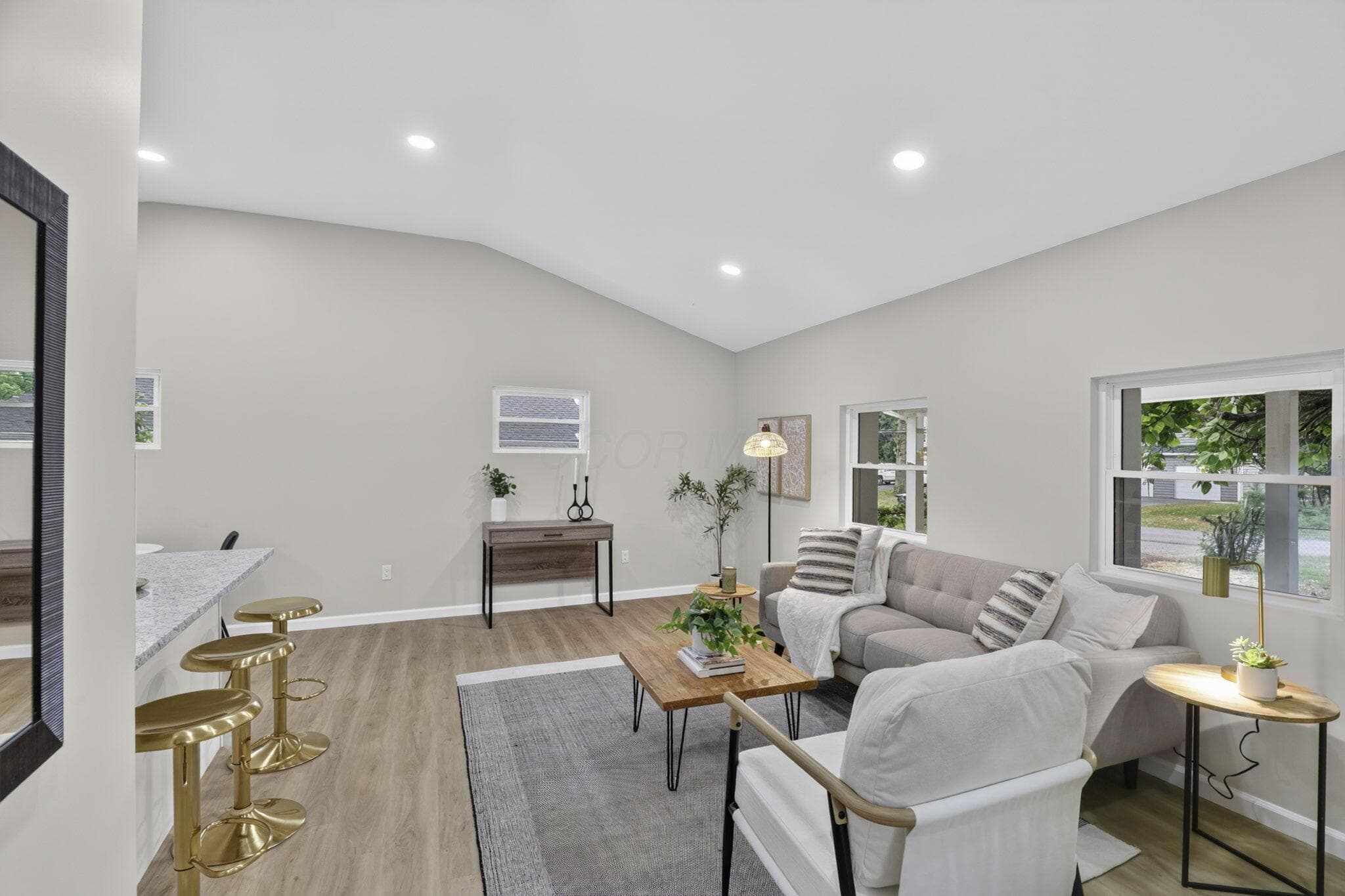 Vaulted ceilings enhance the open-concept living space, featuring recessed lighting and wood-finish flooring