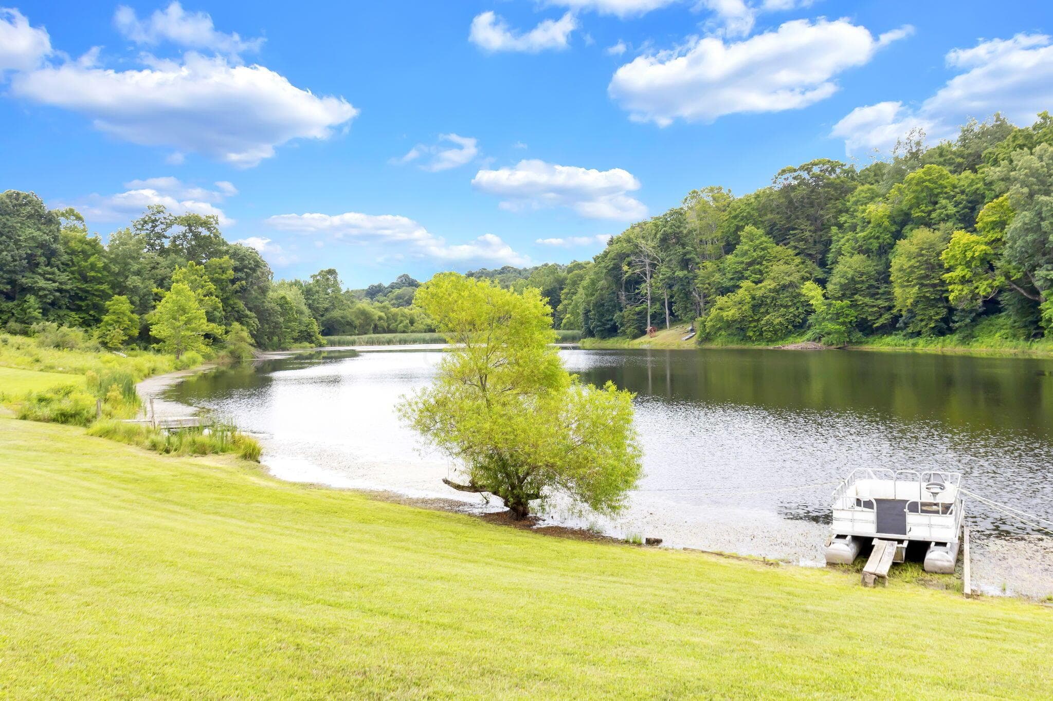 Lakeside property featuring a sprawling grassy slope leading to a private dock and direct water access