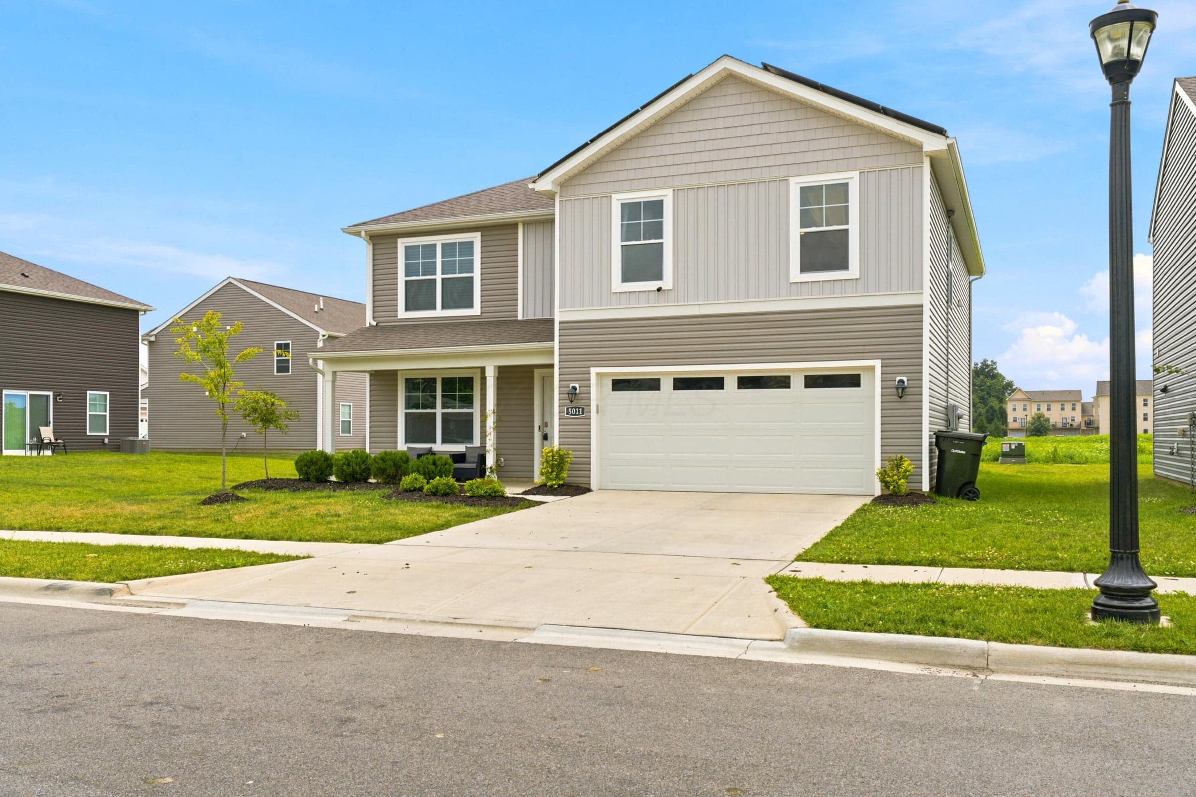 Two-story residence featuring a two-car garage, covered front porch, and multi-toned siding exterior