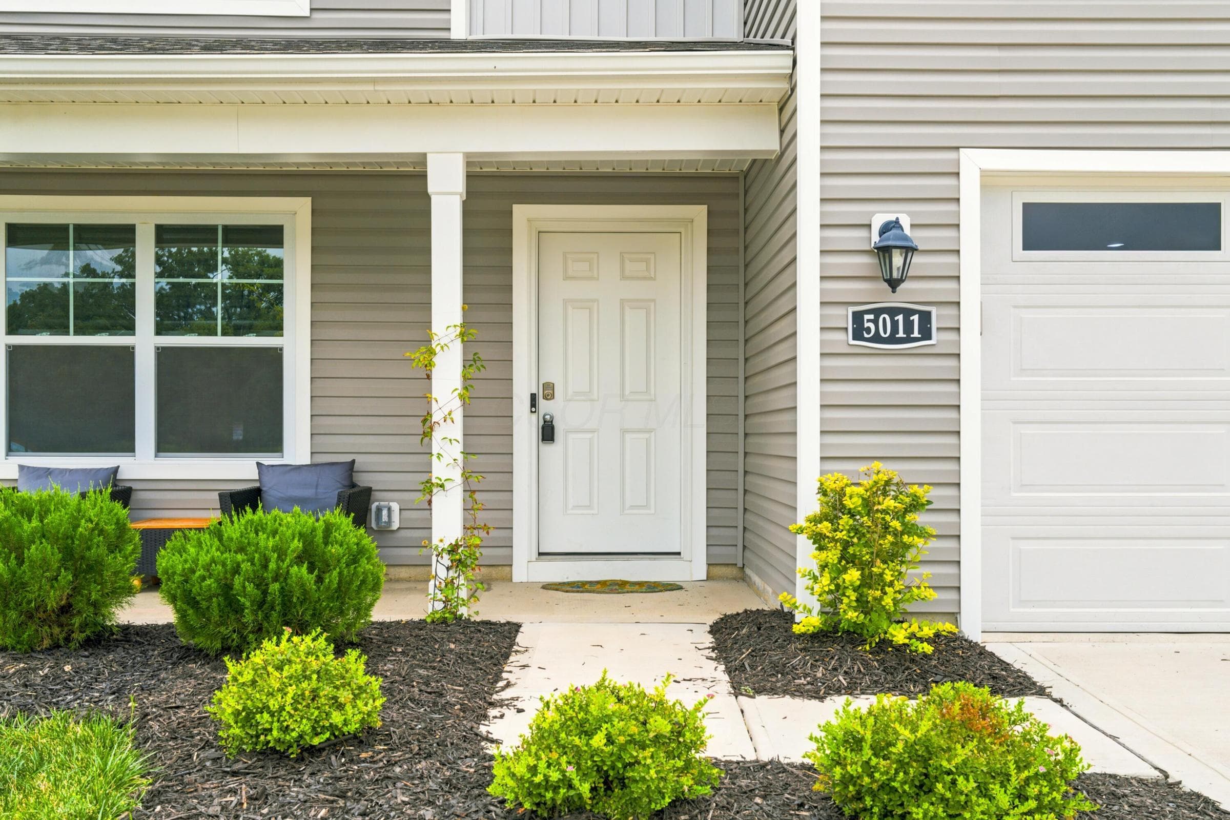 Welcoming front entrance featuring a white paneled door, covered porch, and light gray siding
