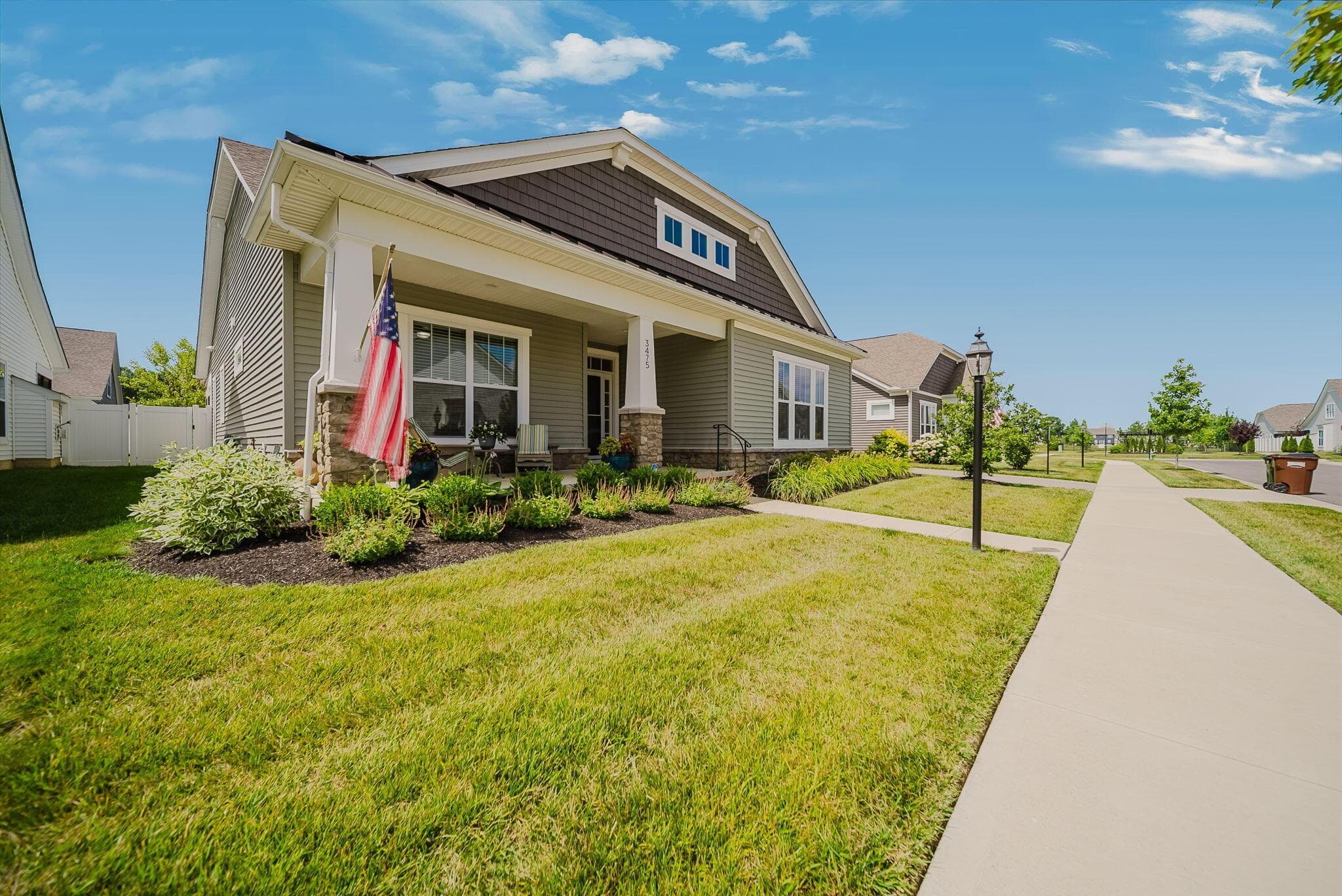 Front exterior featuring a covered porch with stone column accents, horizontal siding, and a shingle roof