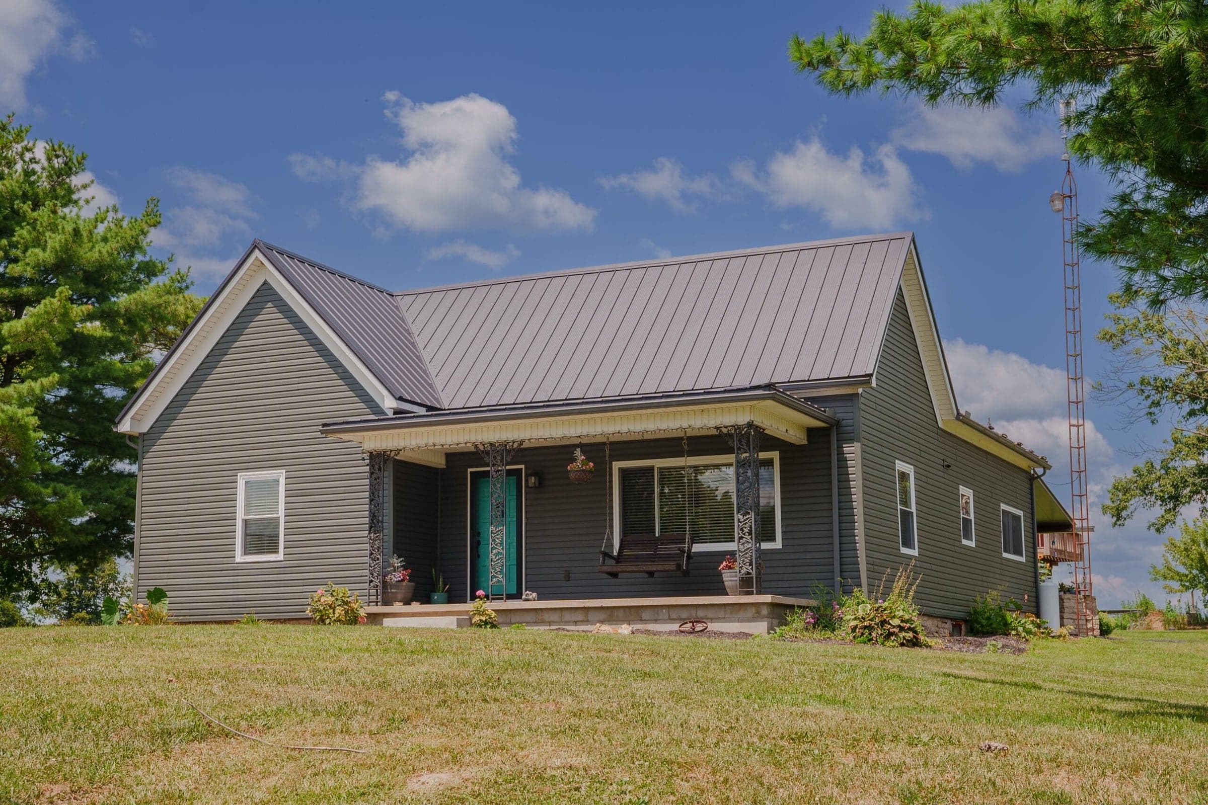 Contemporary farm house featuring grey horizontal siding and a grey metal roof