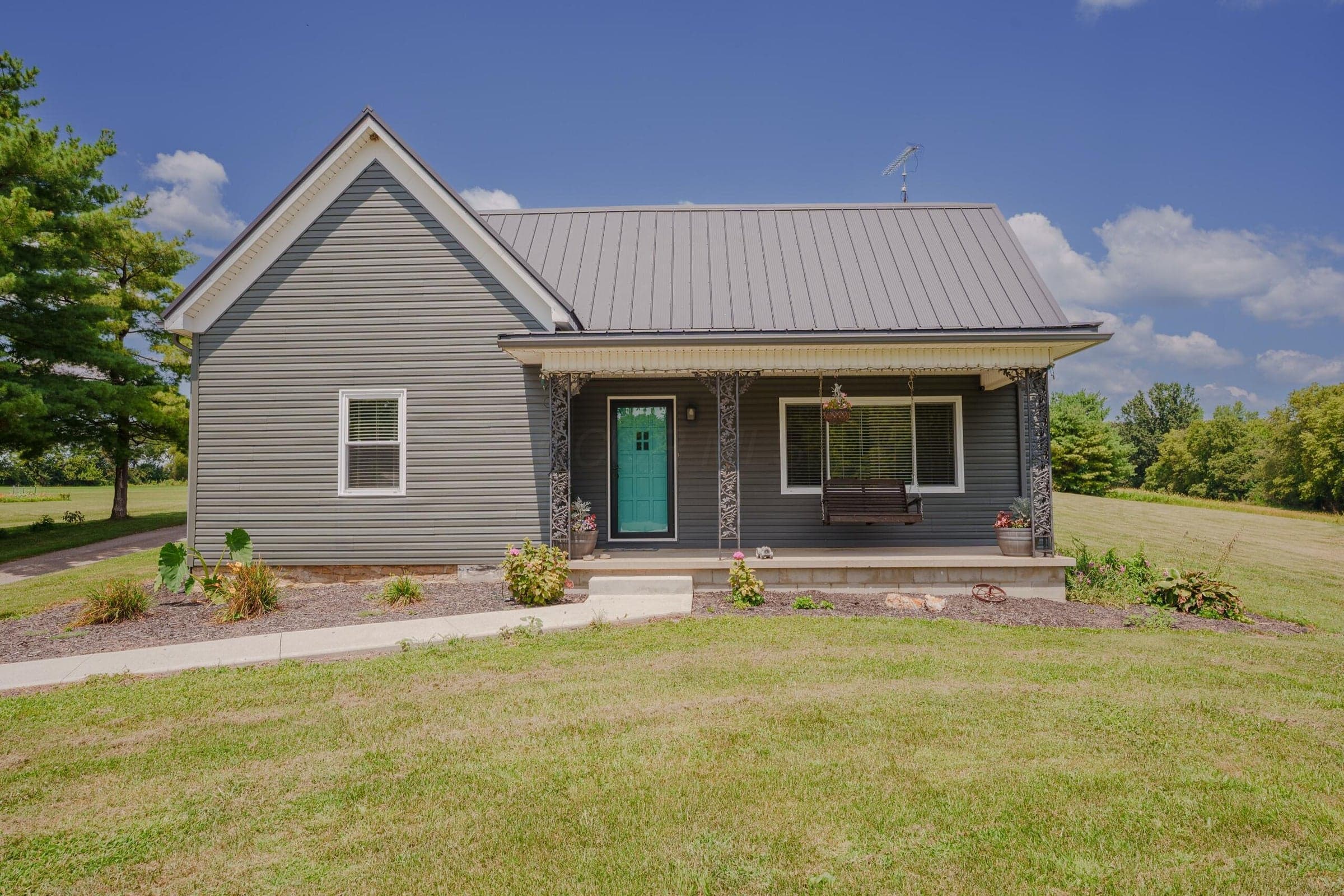 Welcoming front porch with light teal door. Exterior featuring grey siding and a metal roof