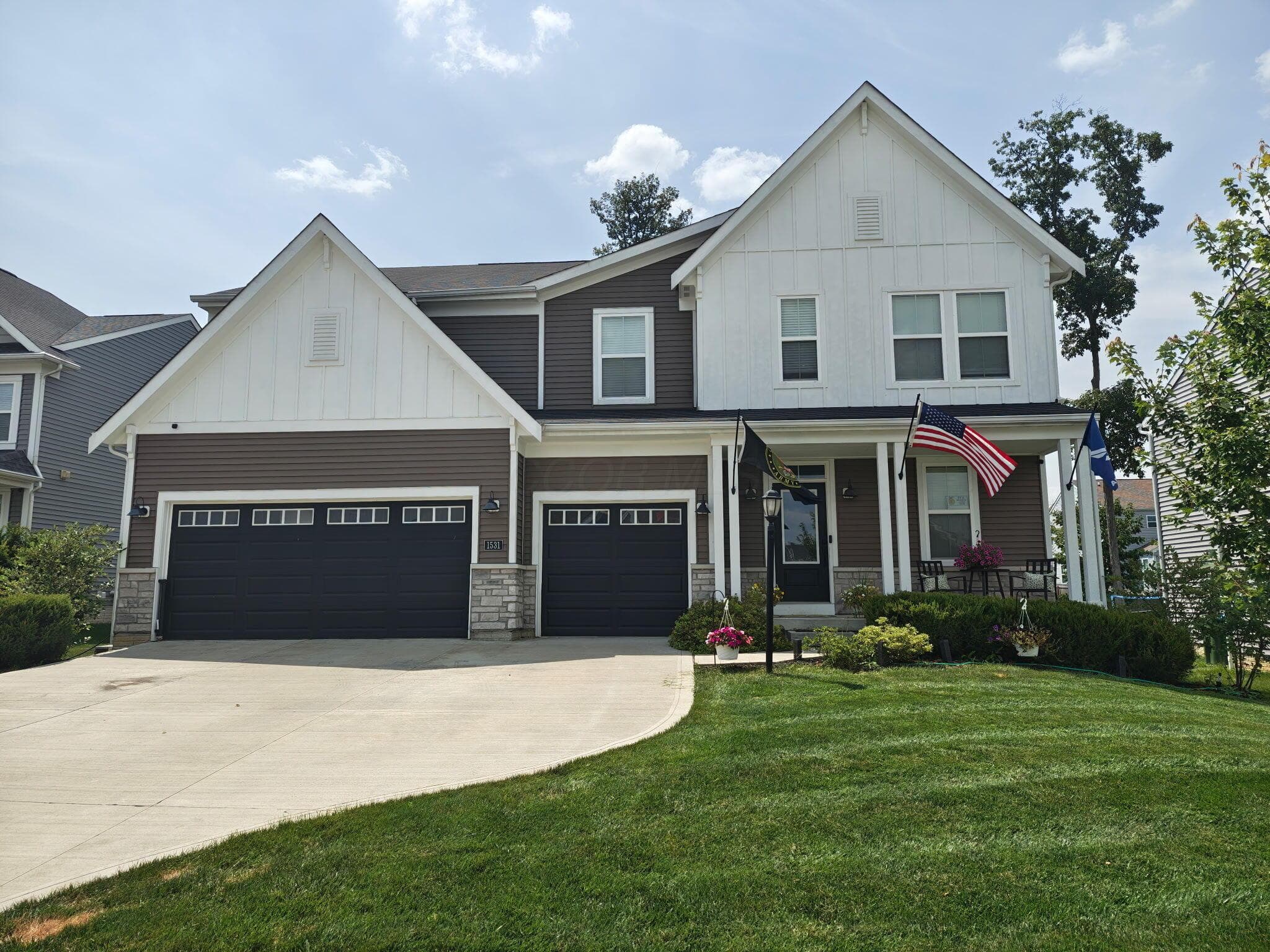 Two-story residence featuring a covered front porch, a 3-car garage, and a manicured lawn