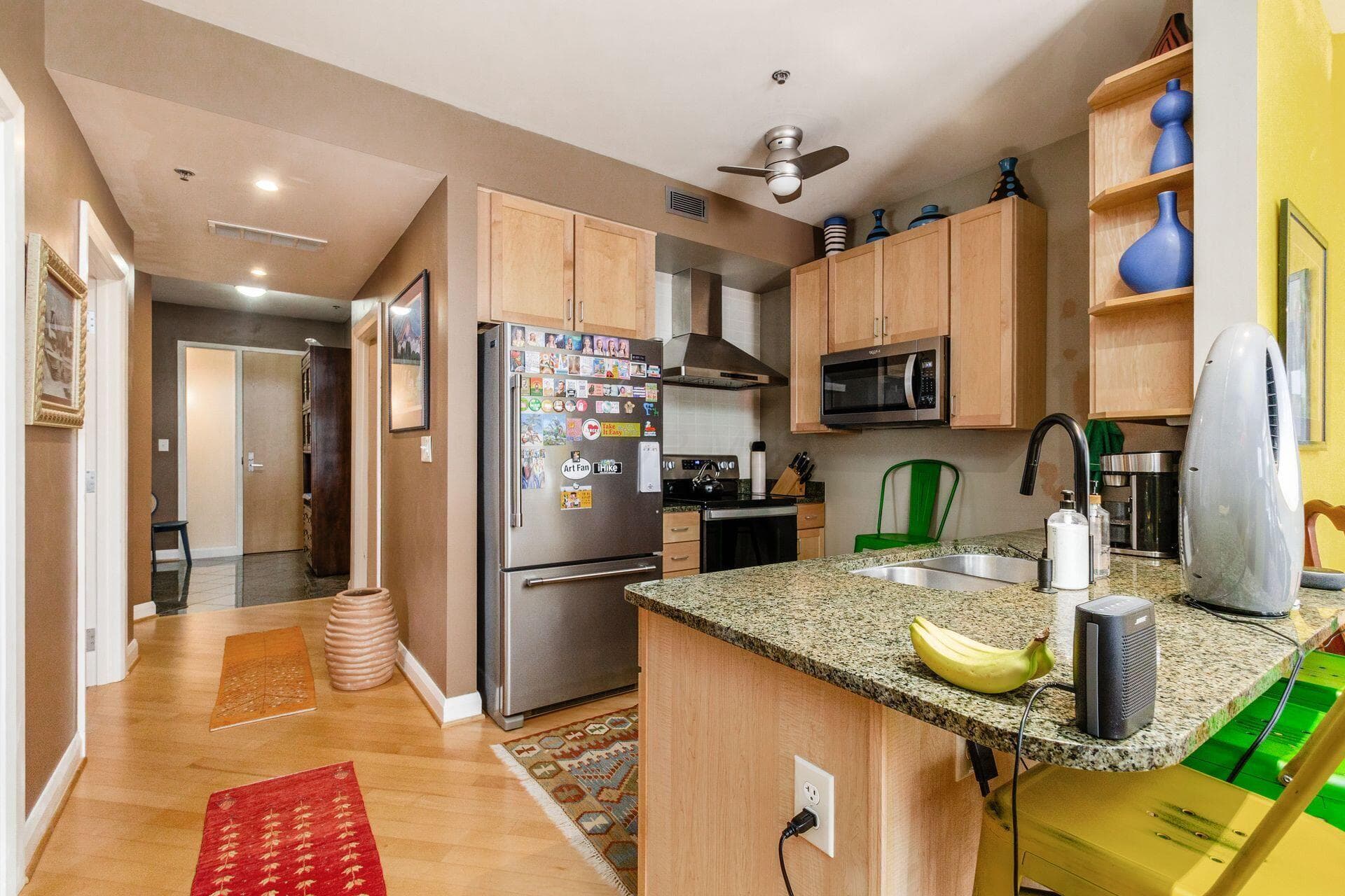 Kitchen featuring wood-finish cabinetry, speckled countertop, stainless steel appliances, and a ceiling fan