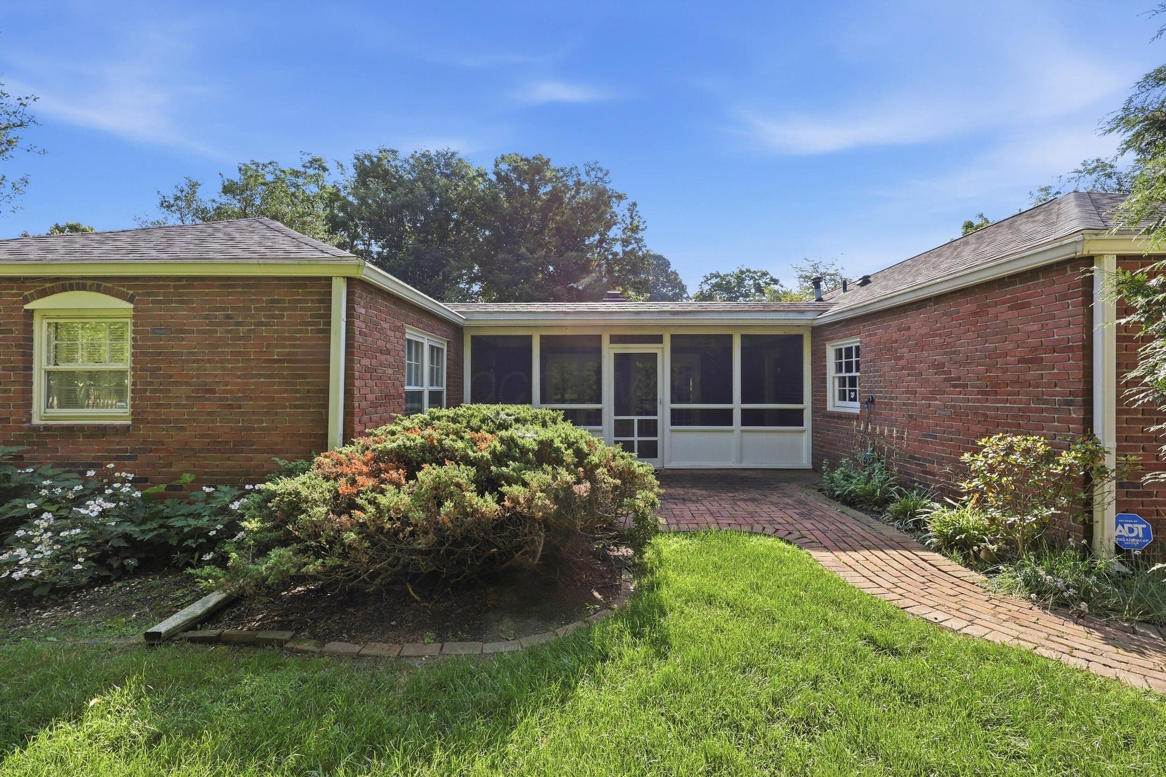 Red brick exterior with a screened porch, a pitched shingle roof, and white-framed windows