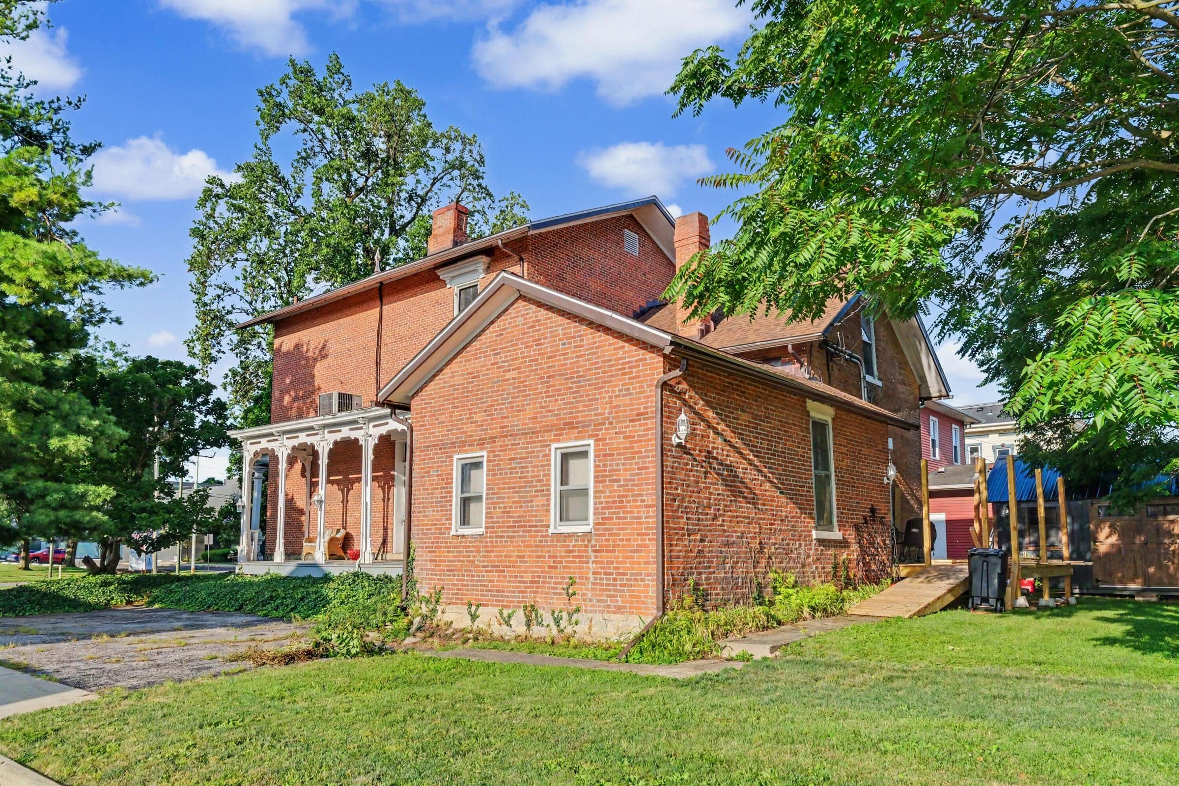 Brick exterior with white trim windows and a covered porch featuring decorative columns