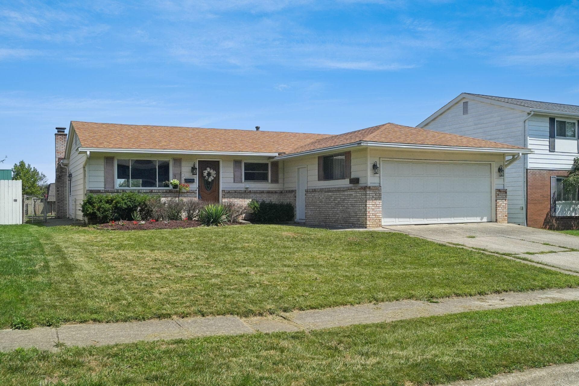 Ranch-style residence featuring a brick and siding exterior, an attached two-car garage, and a front yard with established landscaping