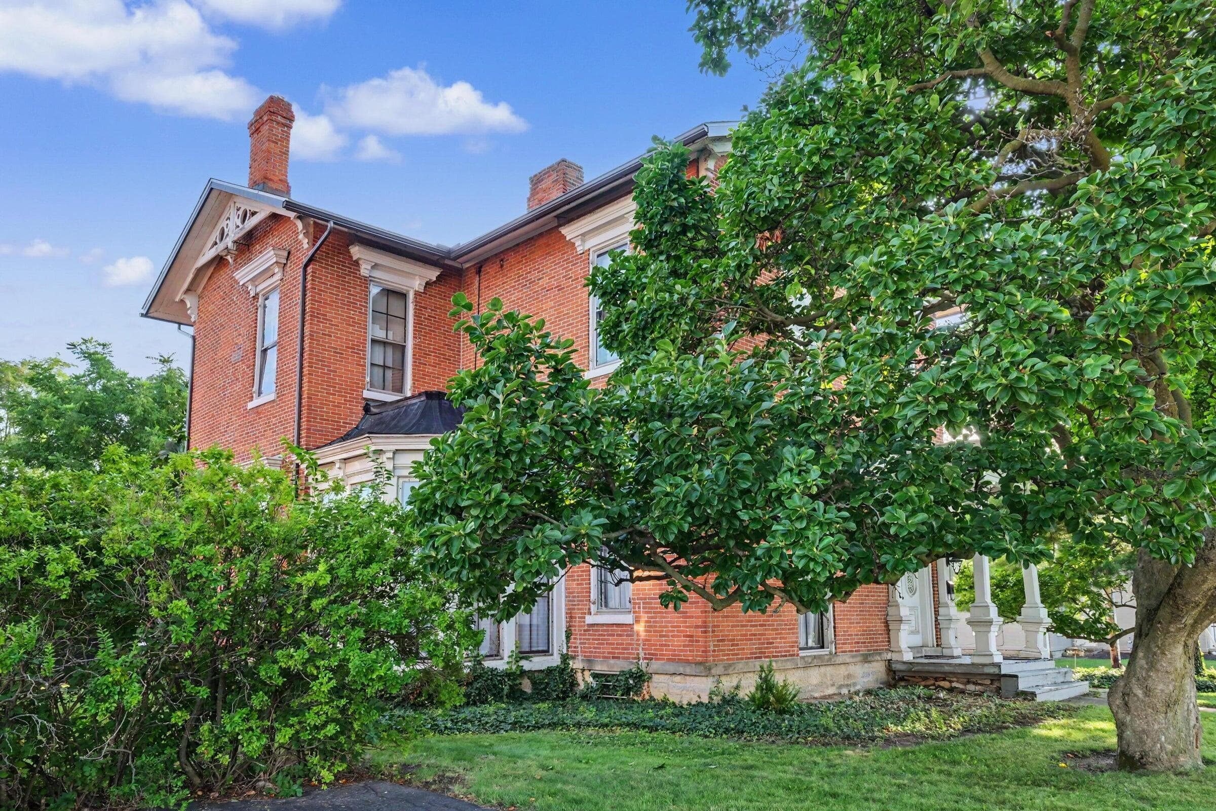 Charming brick residence featuring a classic architectural design with distinctive chimneys, multi-pane windows, and ivy-draped exterior walls