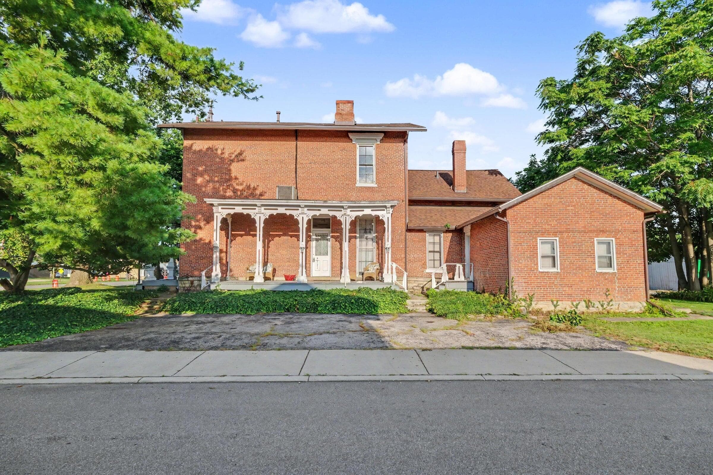 Classic brick Colonial with distinctive columned front portico, featuring symmetrical architectural detailing and period character