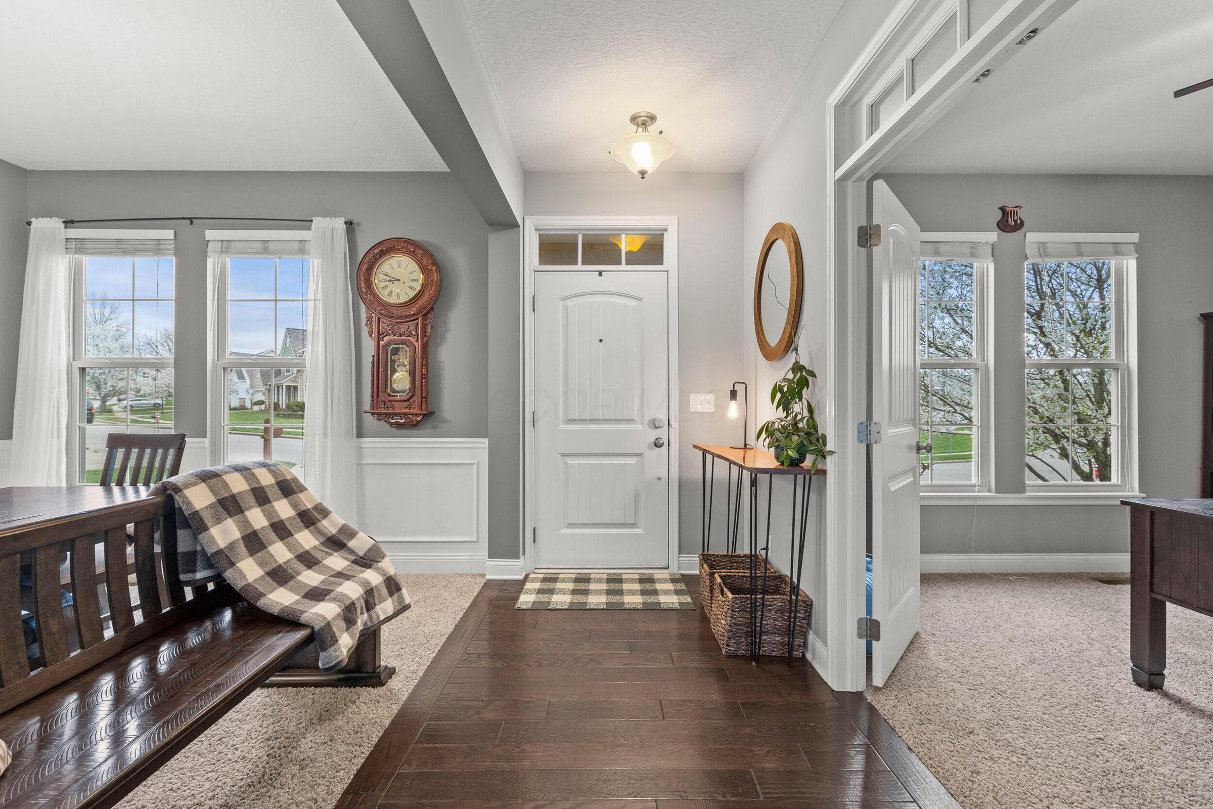 Entryway featuring wood-finish flooring, a white paneled front door with transom window, and prominent windows with grid detailing