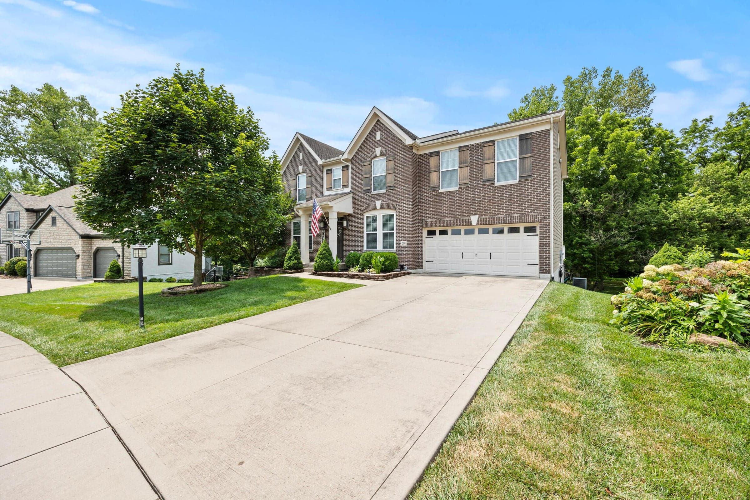 Brick facade with white trim, a double-door garage, and a concrete driveway