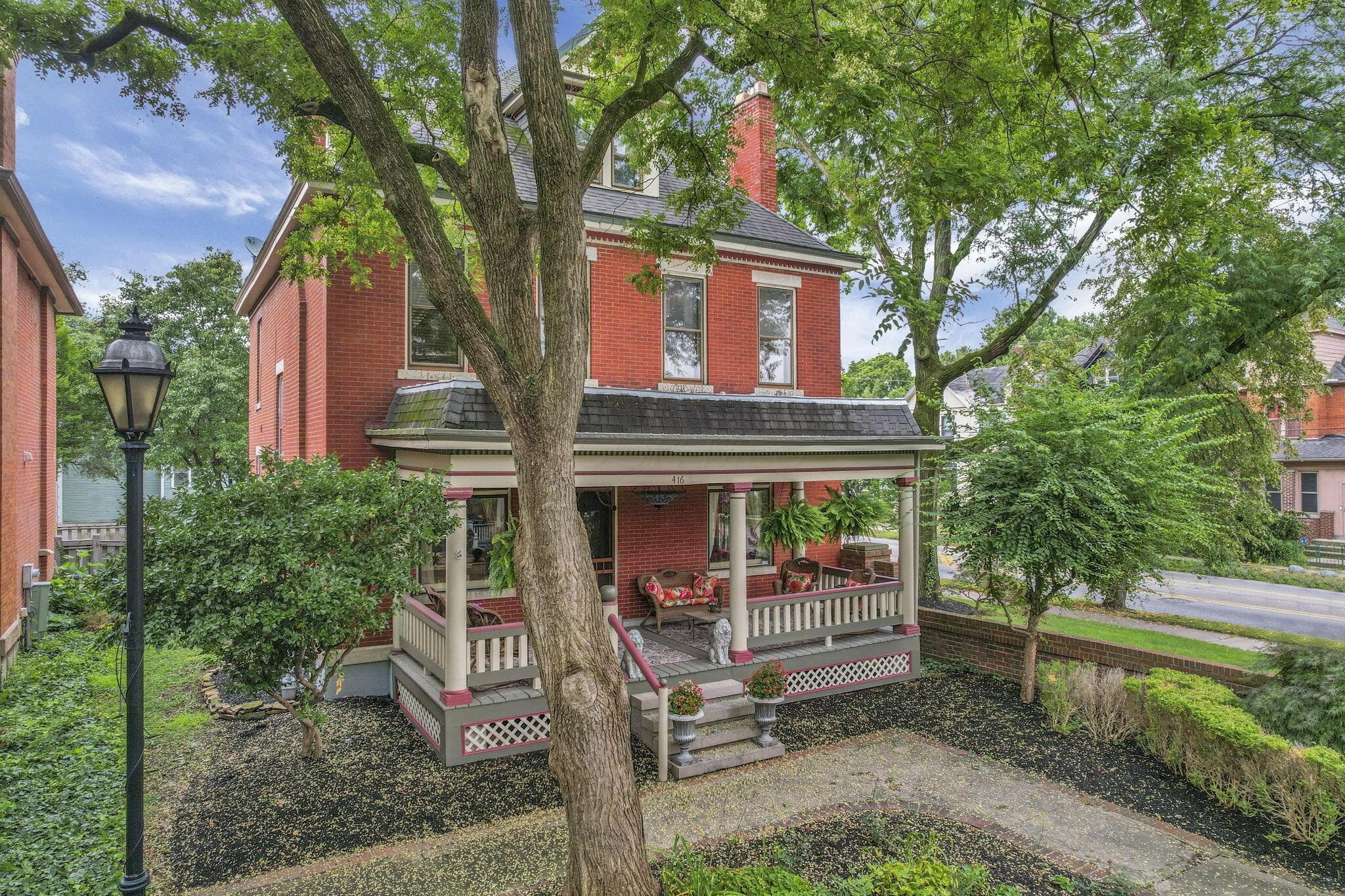 Brick exterior with a covered porch, stone steps, and a decorative railing