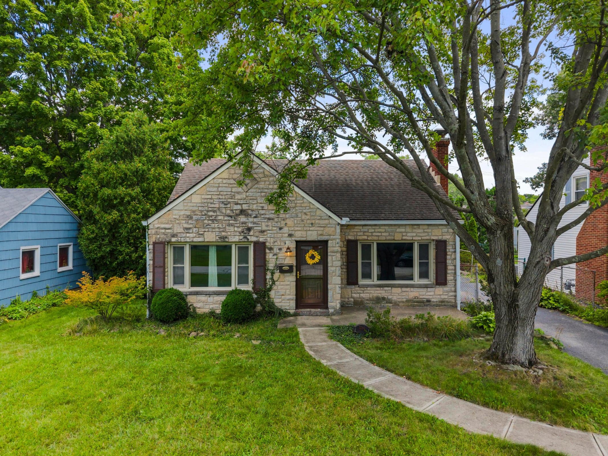 Stone exterior with mature shade trees anchoring the property