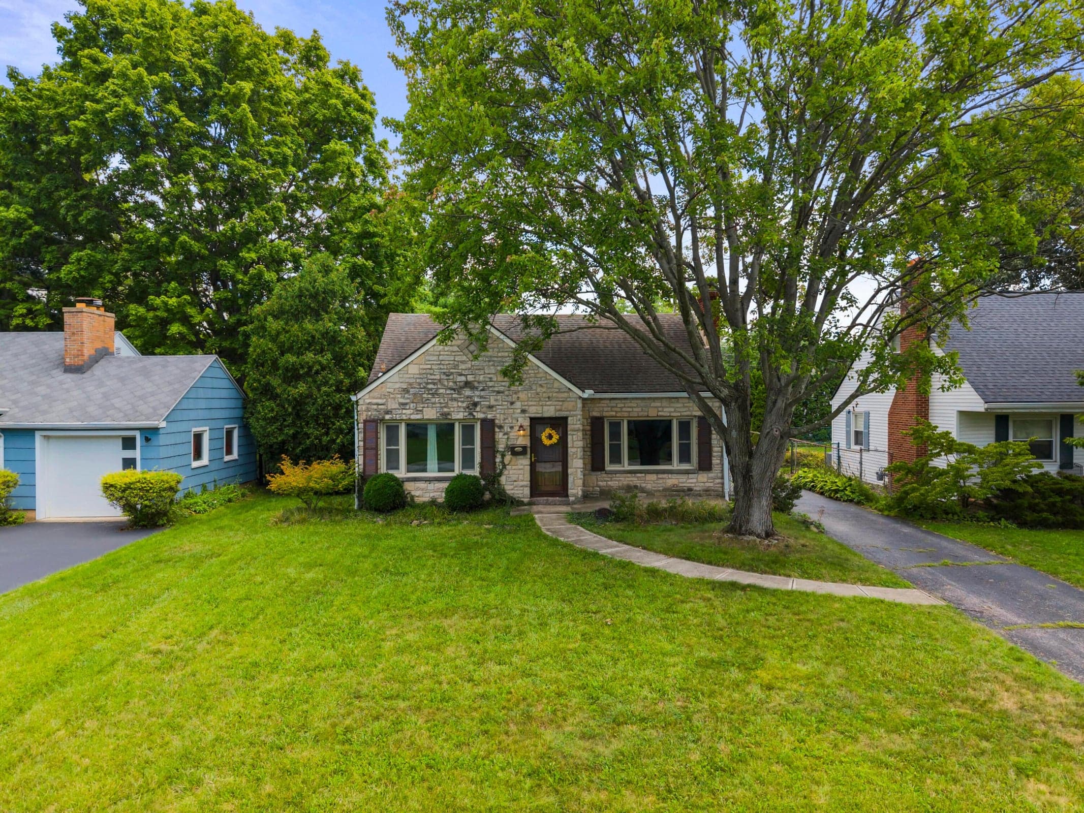 Stone front featuring a welcoming entrance, manicured lawn with defined hardscape pathways