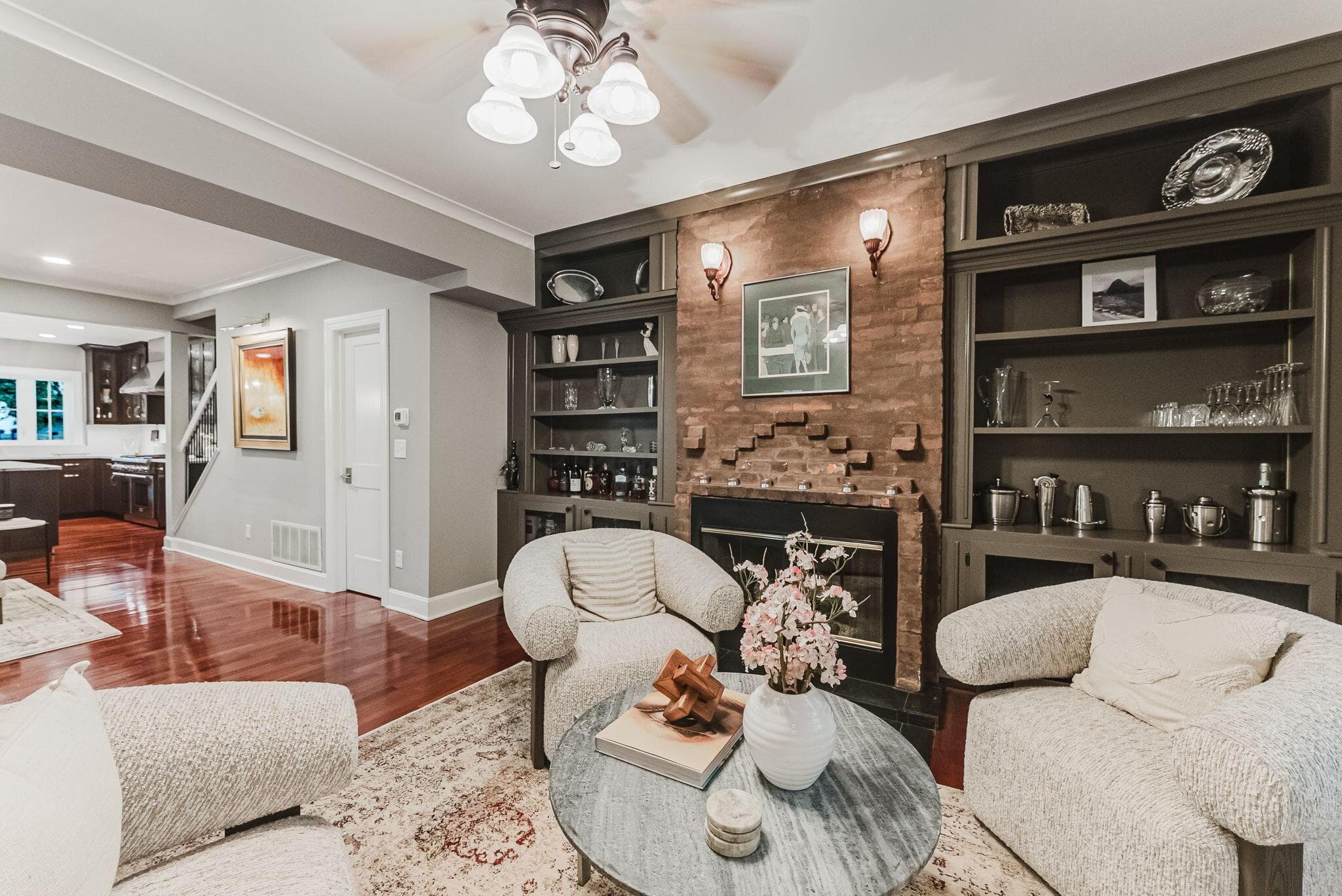 Sophisticated living room showcasing built-in shelving with display niches, an exposed brick fireplace accent wall.