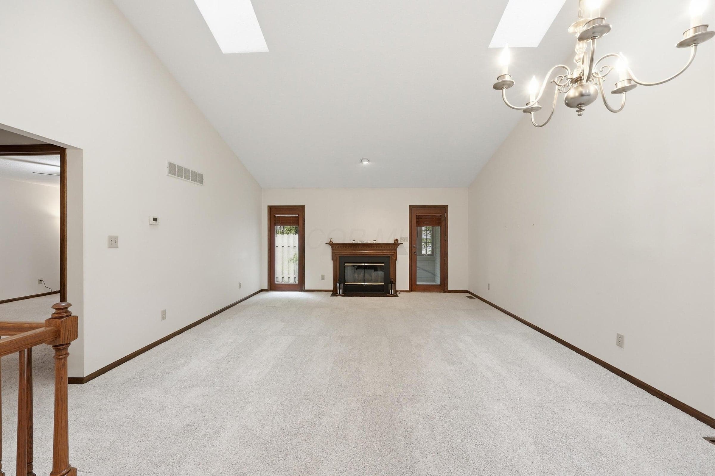 Vaulted ceiling with skylights, fireplace with wood mantel, and door to sun room.