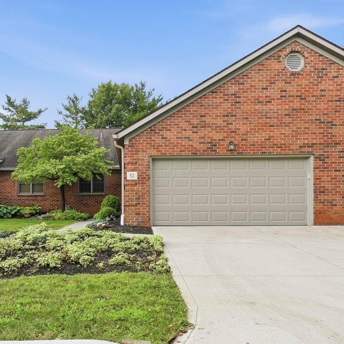 Brick exterior 2 car garage , concrete driveway, and landscaped front yard