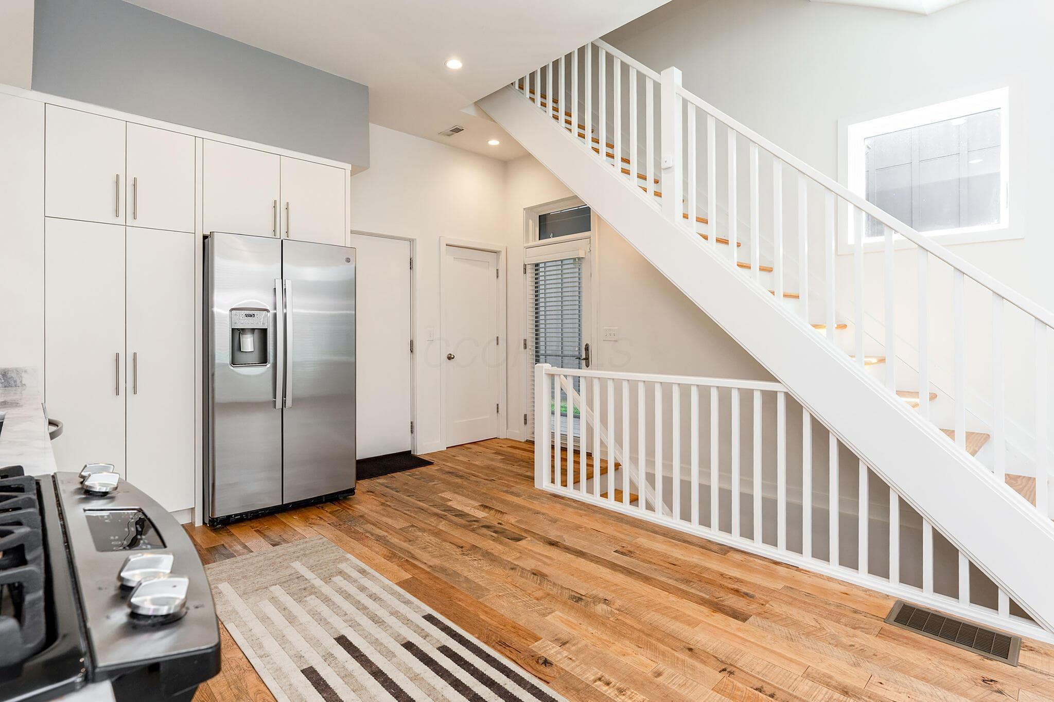 The kitchen has an abundance of contemporary white cabinets, pantry, under counter lighting , stone countertops and stainless steel appliances including a gas range.