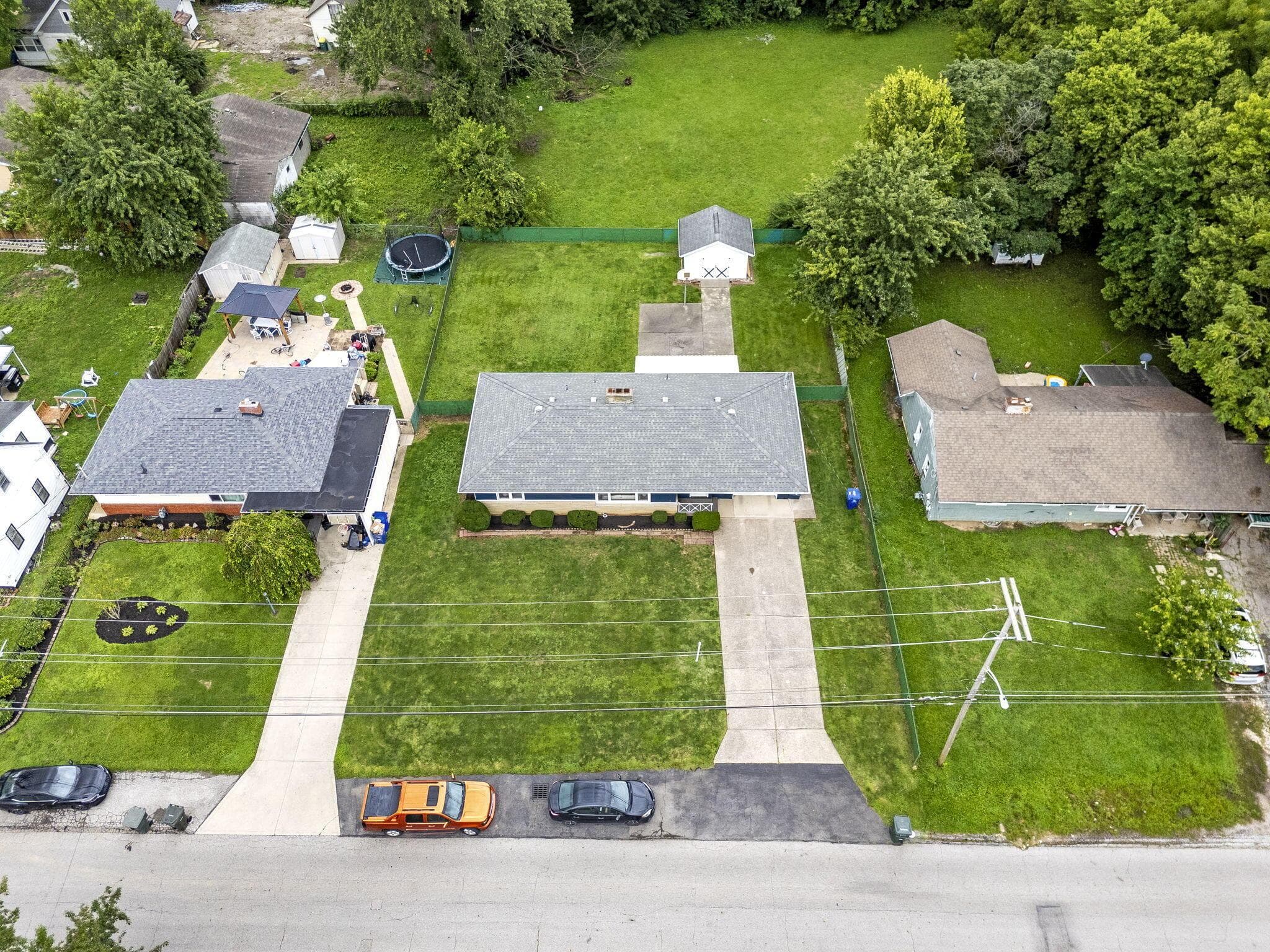 Expansive front lawn with established landscaping, paved driveway, and additional off-street parking