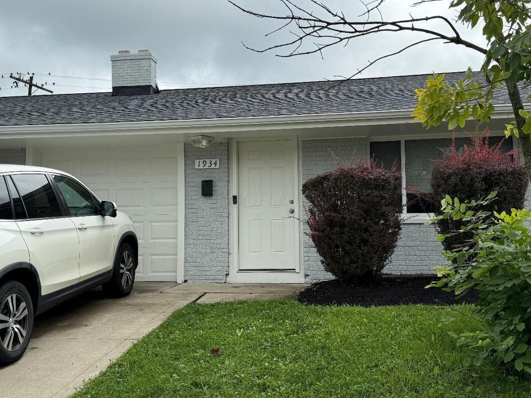 Light gray painted brick exterior with a white front door and a single window