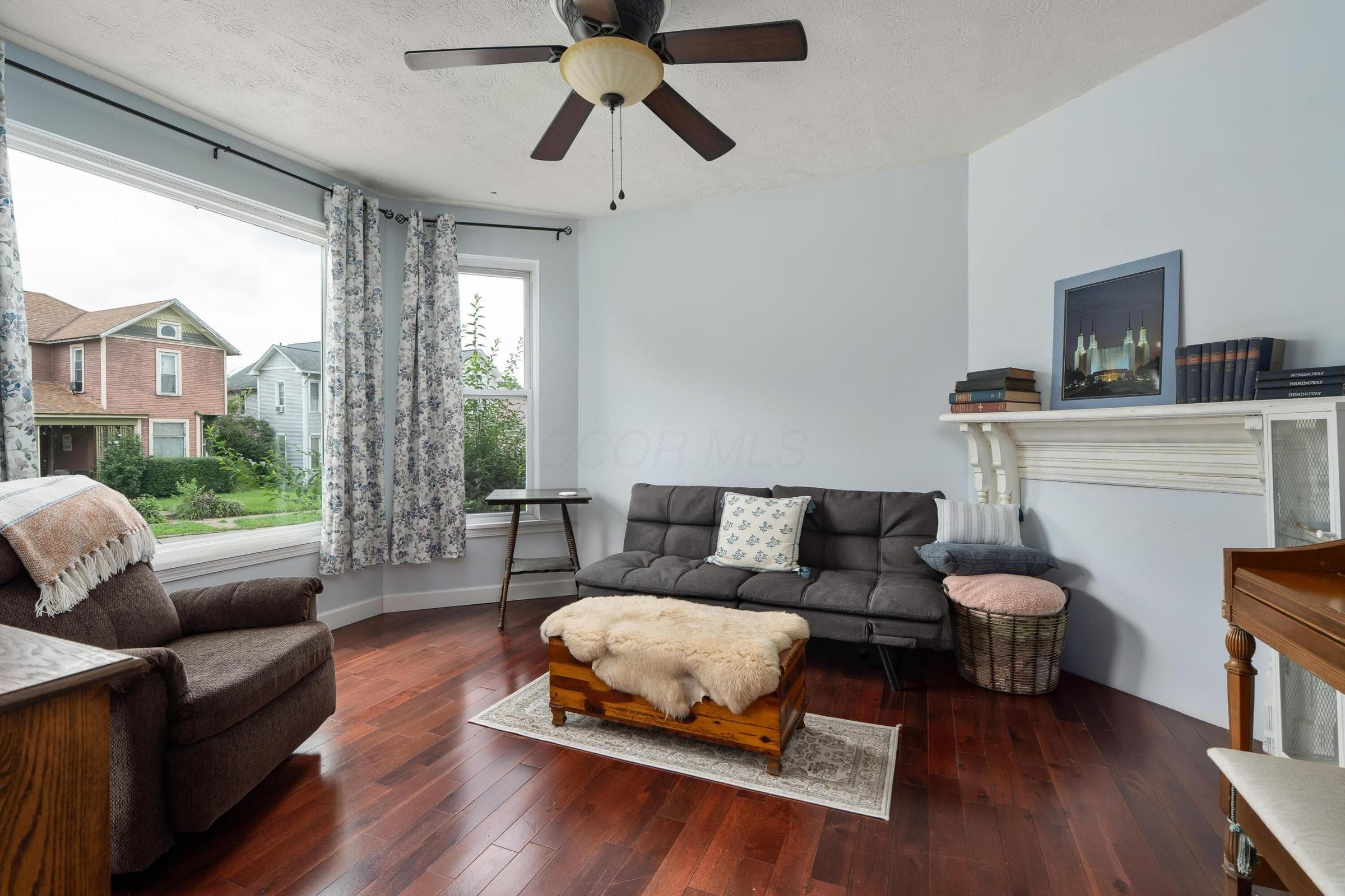 Living room with large windows, wood floors and decorative mantel