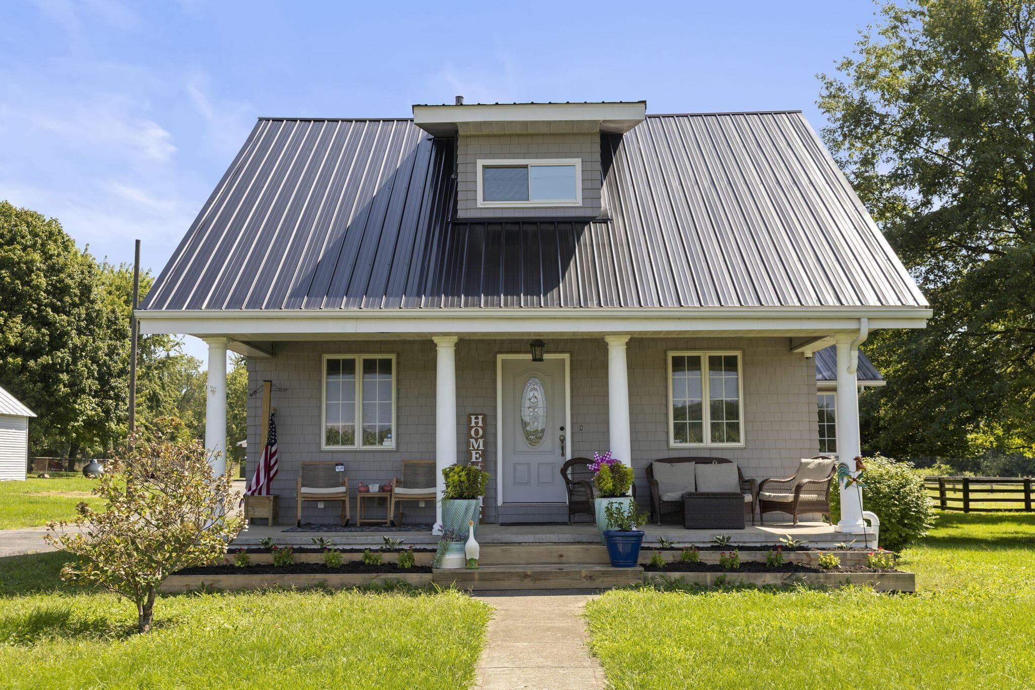 Inviting front porch featuring white columns and a gray metal roof