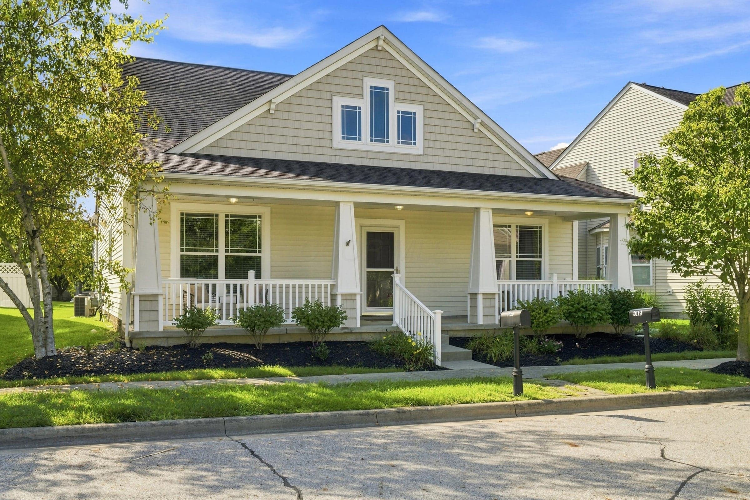 This Craftsman-style home features a covered front porch with white railings and handrail