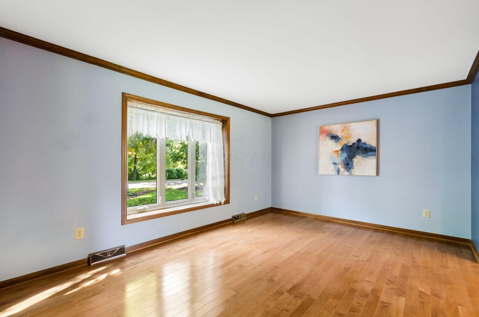 Hardwood flooring, wood trim, and a large window