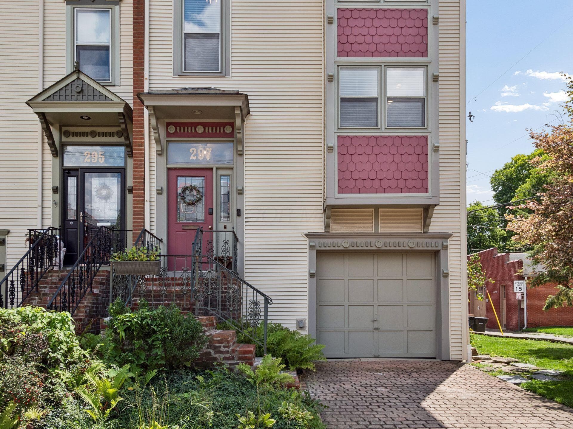 Siding exterior with decorative wood shingles, front entry with brick steps, wrought iron handrails, and an integrated garage