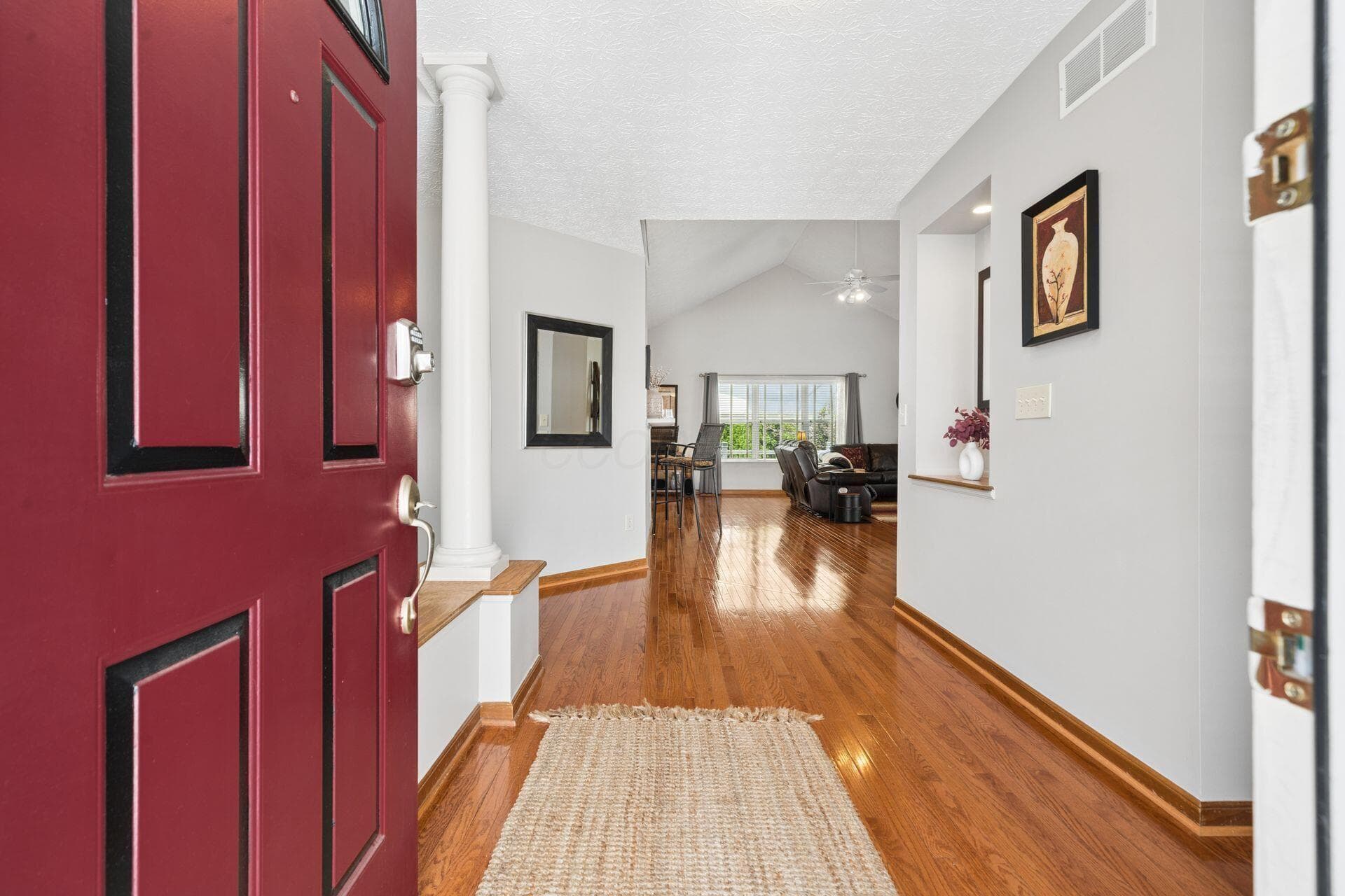 Hardwood flooring, column architectural detail, vaulted ceiling, and recessed wall niche