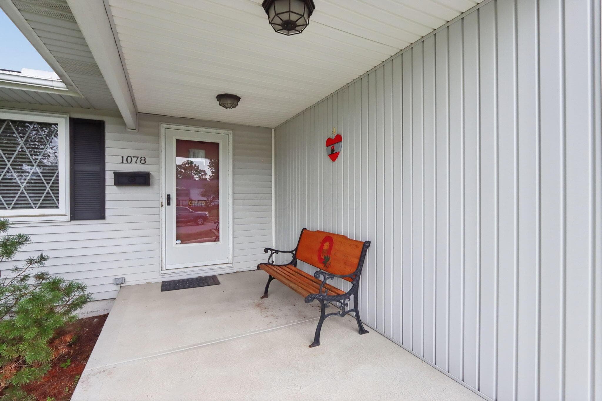 Covered front entry featuring a white paneled storm door and light gray siding