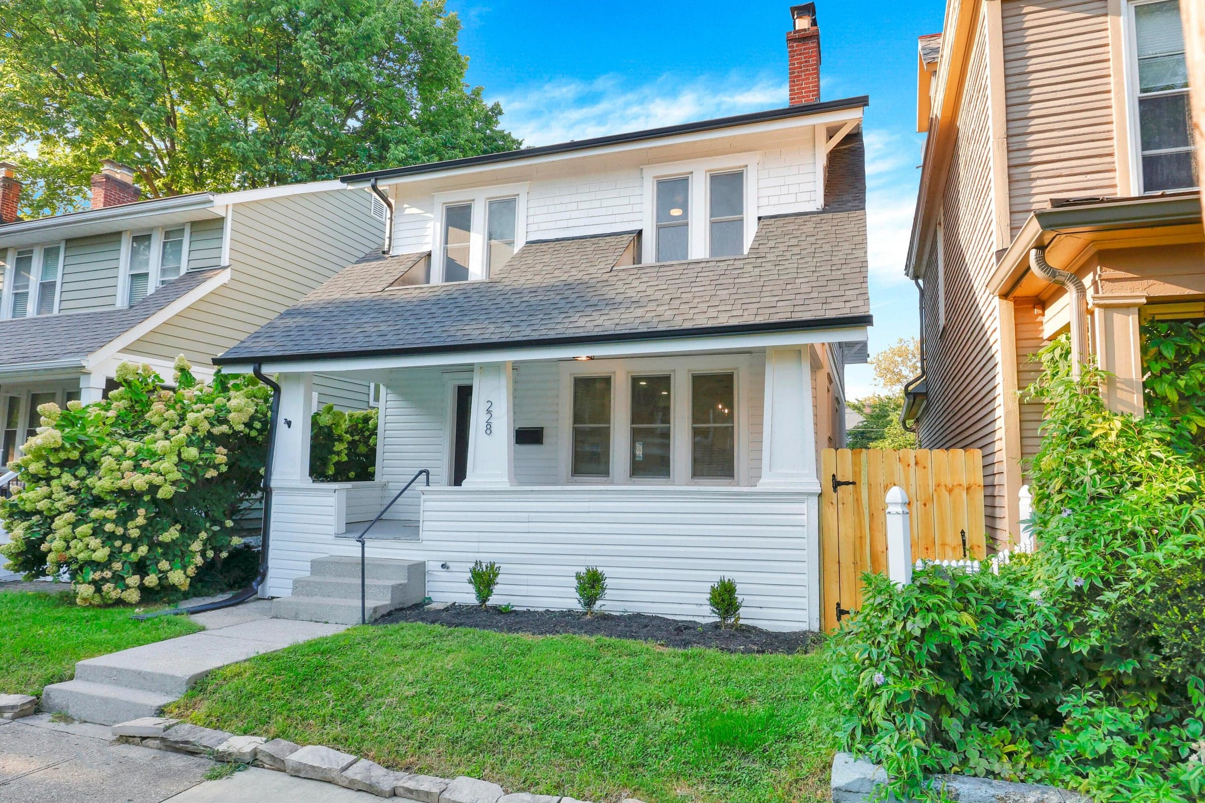 White siding exterior with a dark shingle roof, a covered front porch, and a concrete pathway