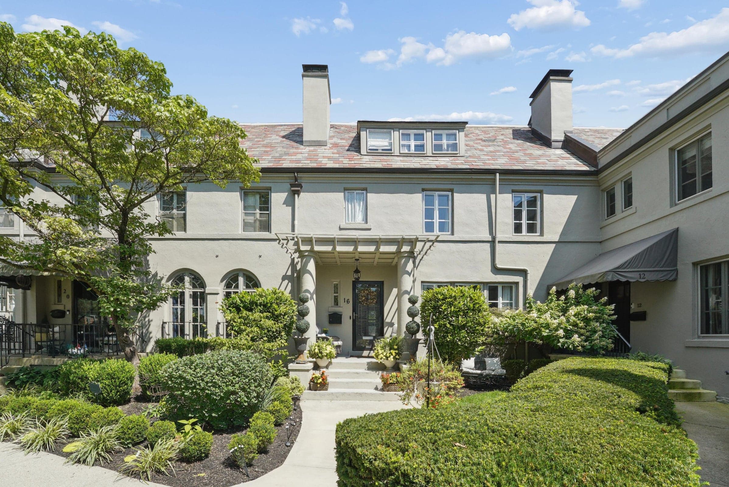 Stucco exterior with a tiled roof, multiple dormer windows, and a prominent chimney