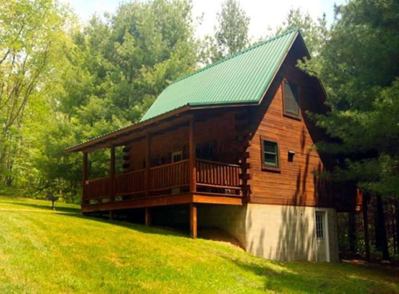 Classic log-cabin exterior with covered porch and wooded surroundings.