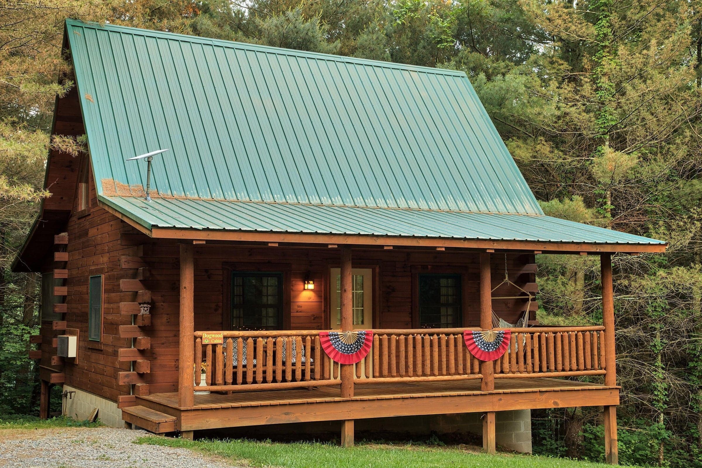 Dogwood Cabin covered front porch surrounded by the peaceful wooded setting, offering additional outdoor living and relaxation space.