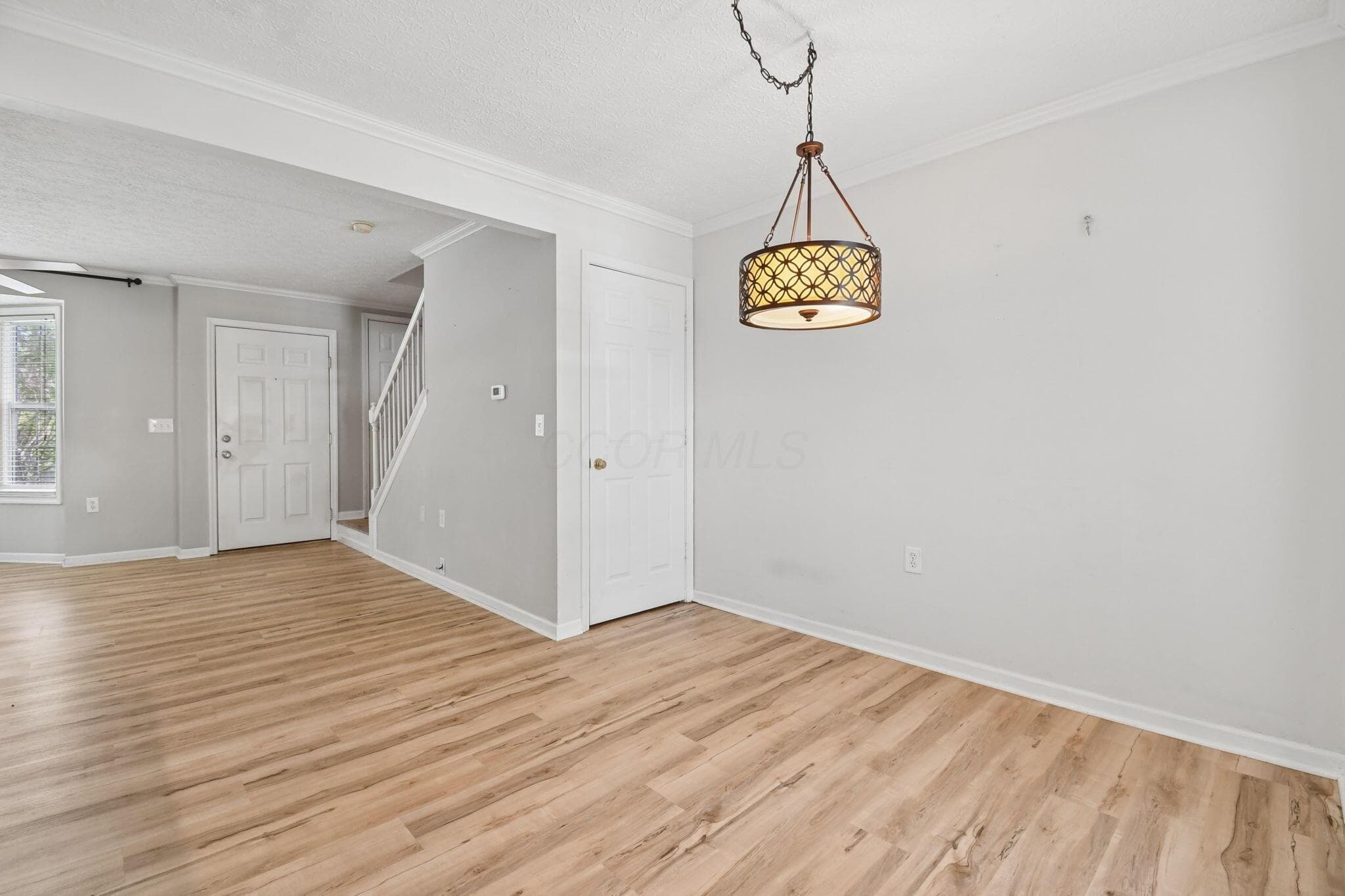 Wood-finish flooring throughout, white trim molding, and a decorative pendant light fixture